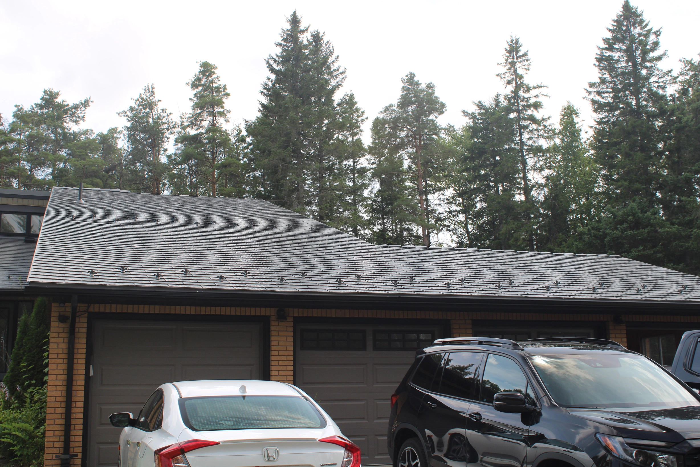 Musket Grey Interlock Cedar Shingle aluminum roof on a two-storey modern home with a metal roof among tall trees, Mono, Ontario