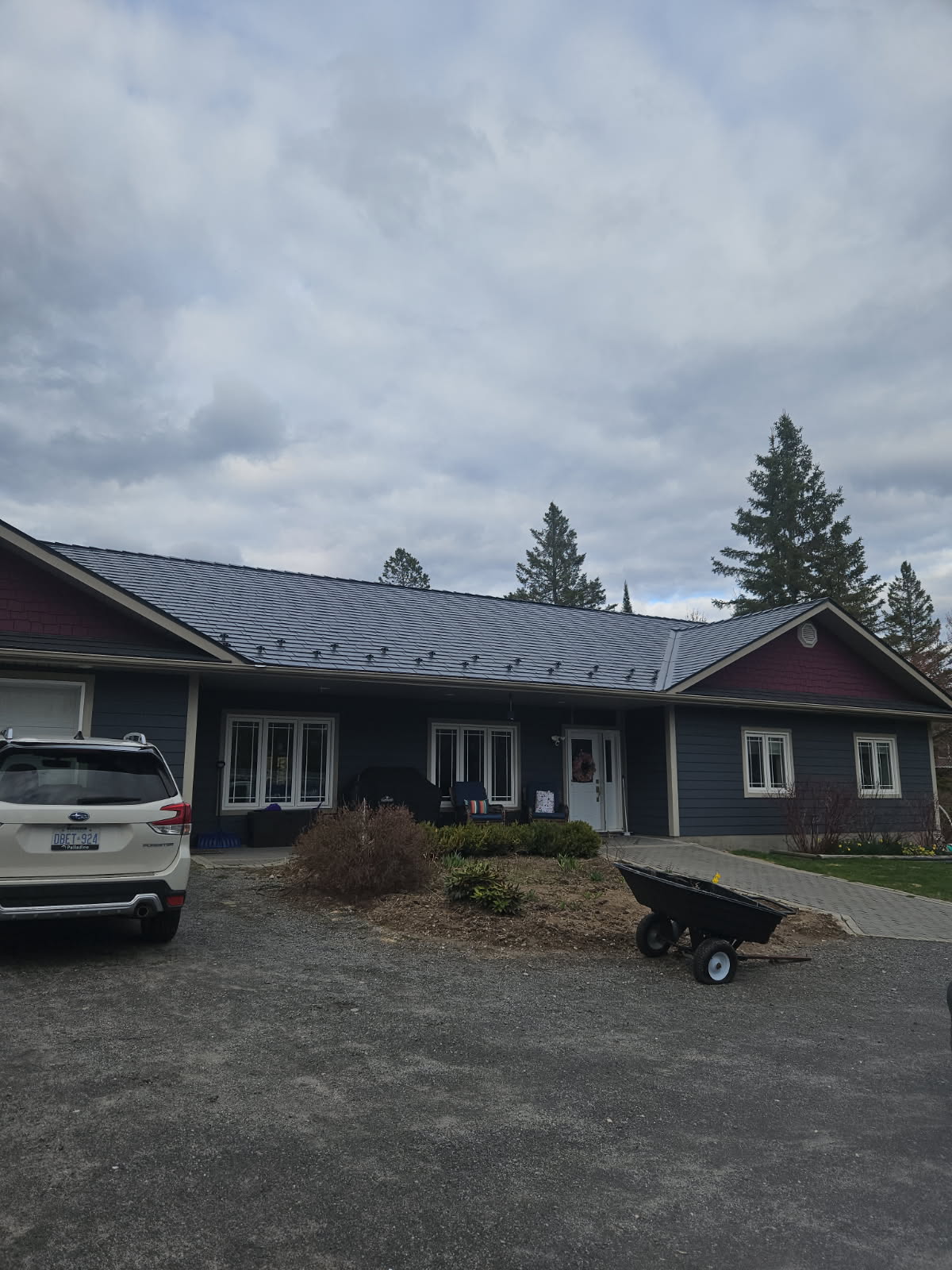 Front elevation of a single-storey ranch home in Sudbury, ON featuring Interlock deep charcoal cedar shingle aluminum metal roofing with snow guards.