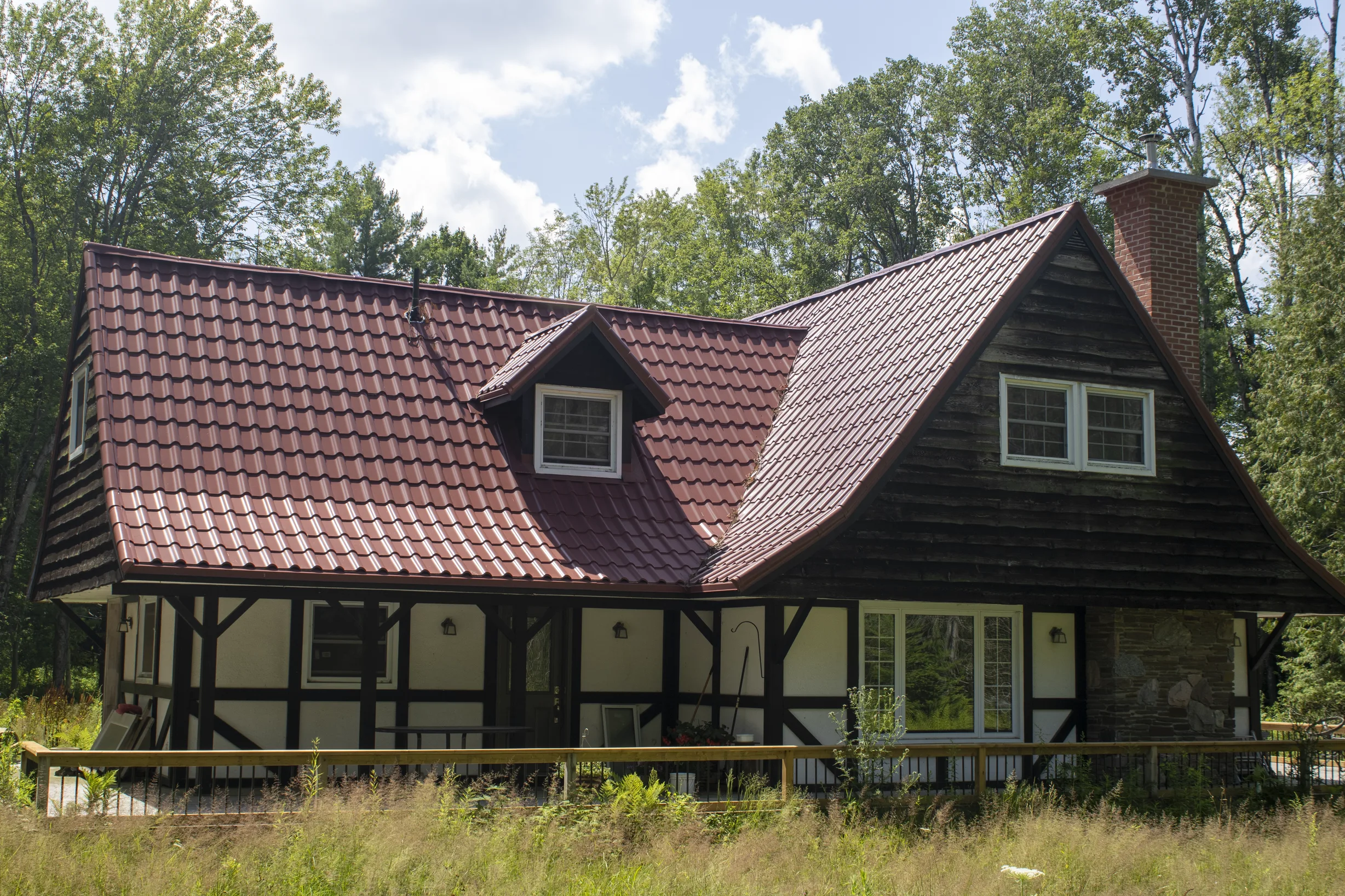 Tile Red Interlock Tile aluminum roof on a red roofed chalet with a porch and tall trees, Gravenhurst, Ontario