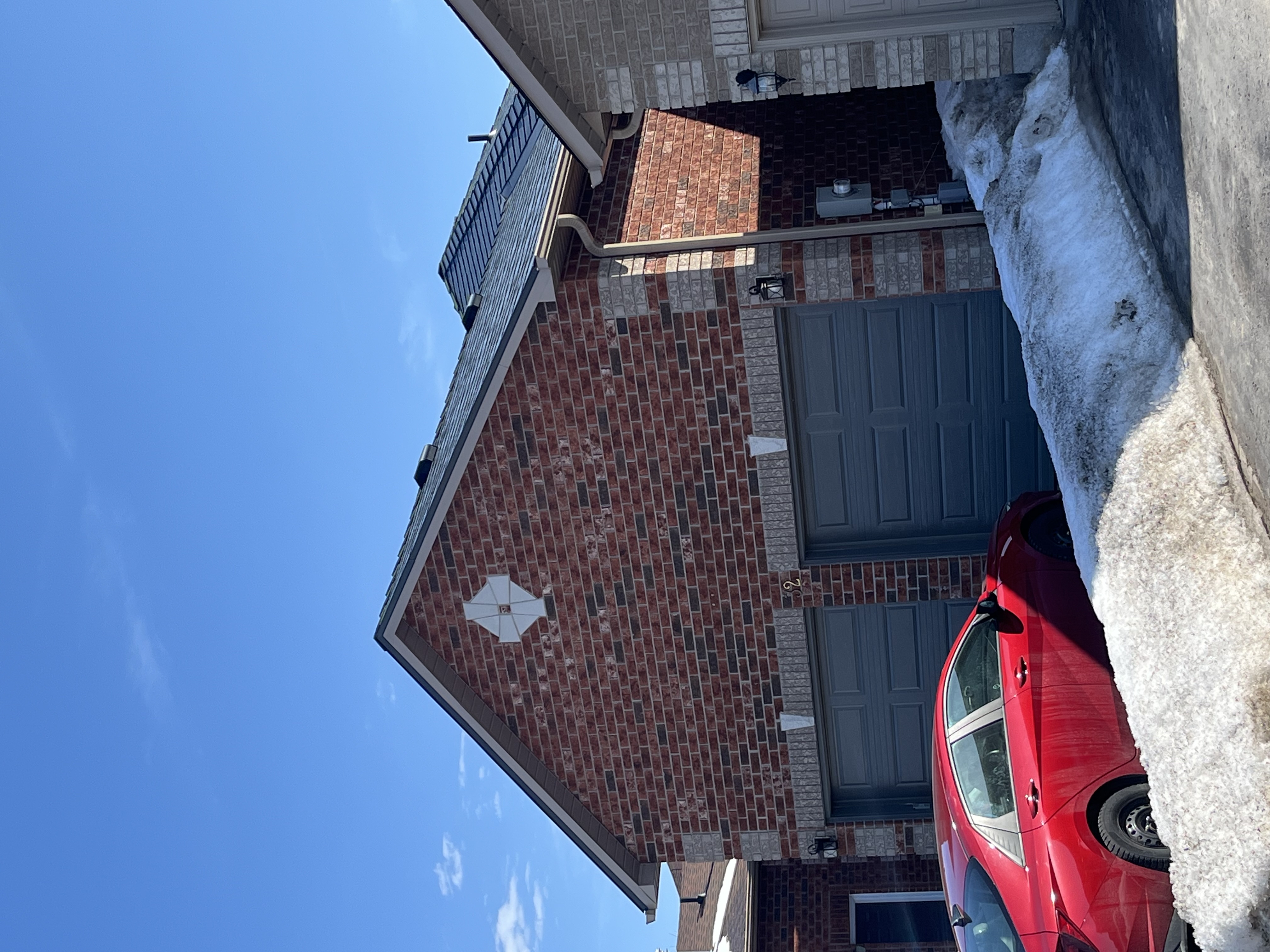 Deep charcoal Interlock aluminum slate metal roof on a two-storey red brick home with double garage, photographed in winter in Barrie, ON.