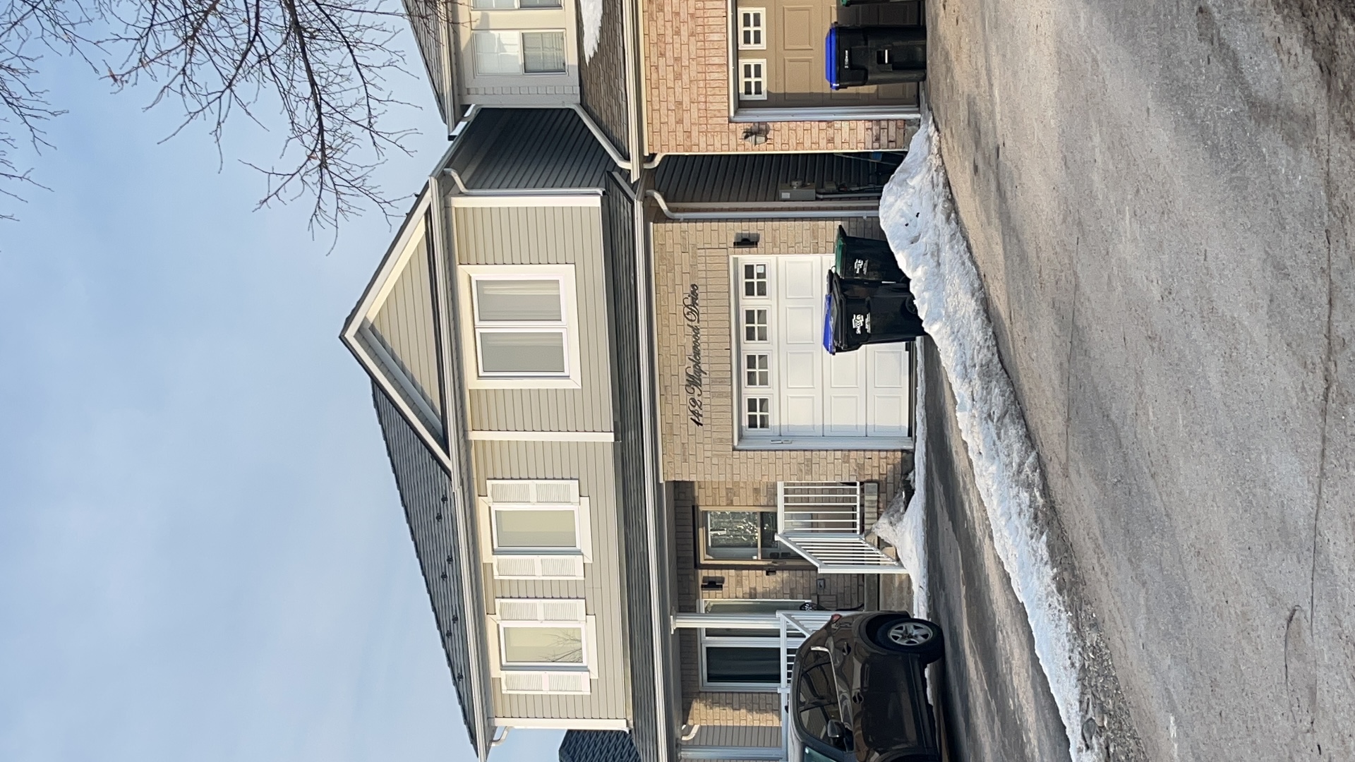 Two-storey suburban home at 142 Maplewood Drive, Angus ON, with black Interlock aluminum slate metal roofing on a medium-pitch gable, tan vinyl siding, and brick facade.