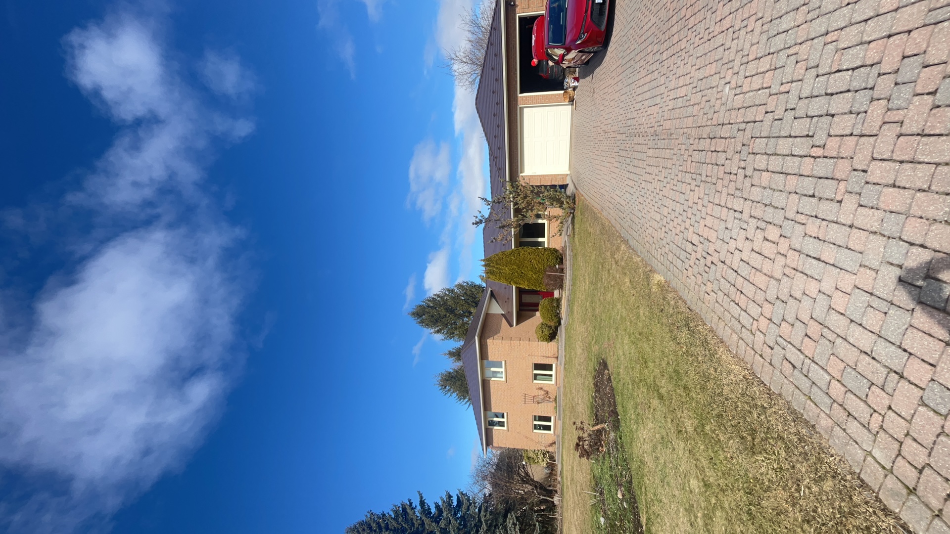Two-storey brick Colonial home in Bradford ON with Interlock Colonial Brown cedar shingle metal roof, wide interlocking paver driveway, and attached two-car garage.