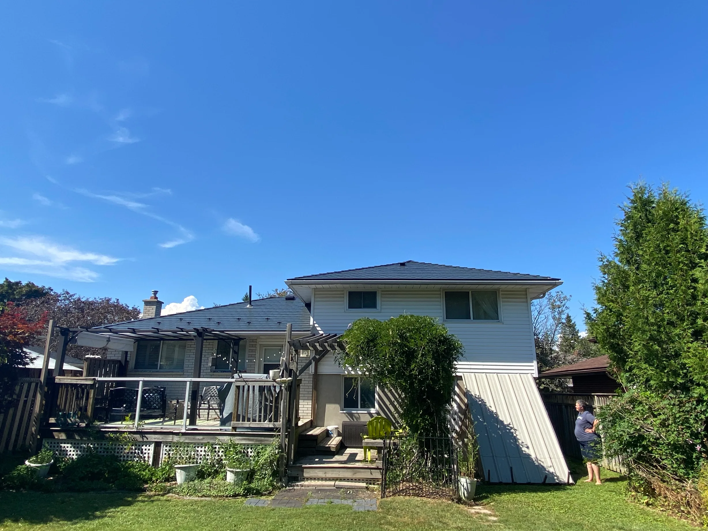 Deep Charcoal Interlock Slate aluminum roof on a two-storey white home with a metal roof in a suburban yard, Belleville, Ontario