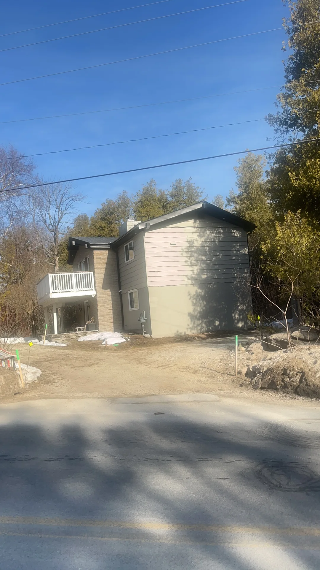 Black Interlock Slate aluminum roof on a grey two-storey home with a metal roof among trees, The Blue Mountain, Ontario