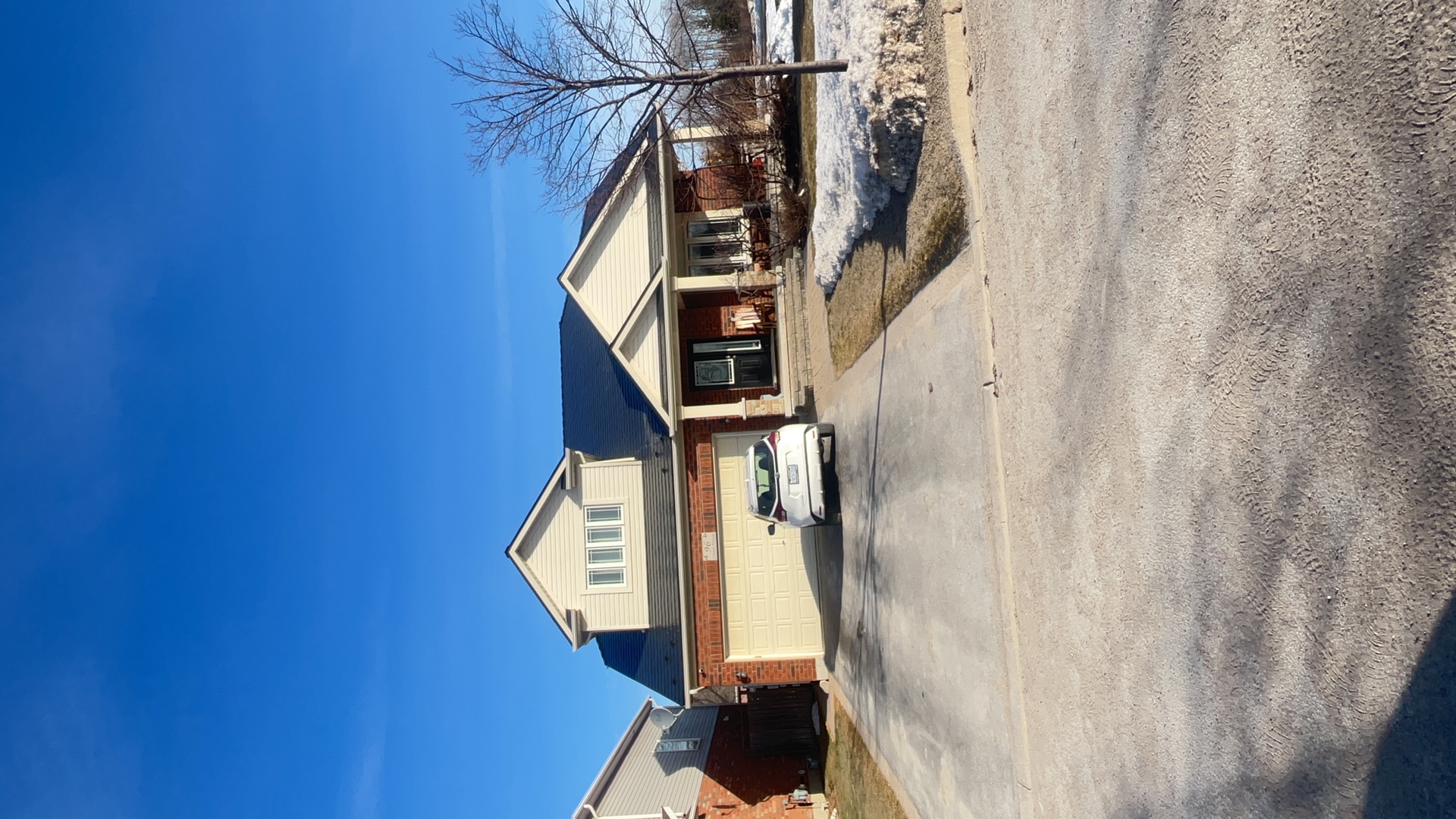 1.5-storey Craftsman home in Collingwood ON with black Interlock aluminum slate metal roof, front dormer, and brick facade on a clear winter day.
