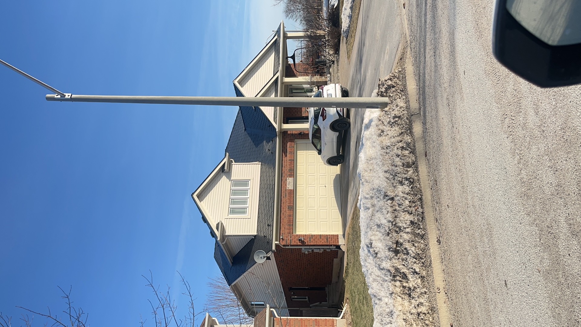 Street view of a brick single-family home in Collingwood ON with a black Interlock aluminum slate metal roof featuring multiple gable peaks and a covered porch.