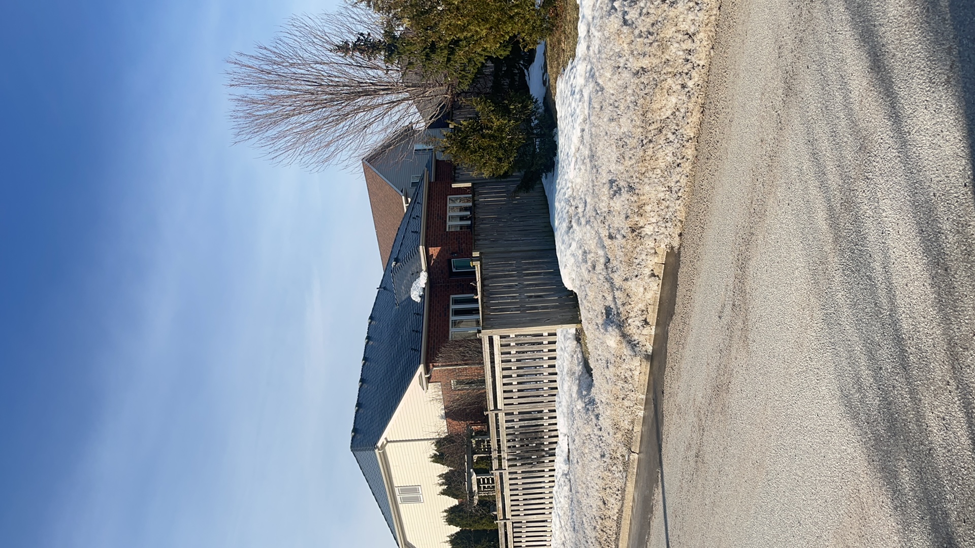 Black Interlock aluminum slate metal roof on a 1-storey brick ranch home in Collingwood, ON, viewed from the street in winter.