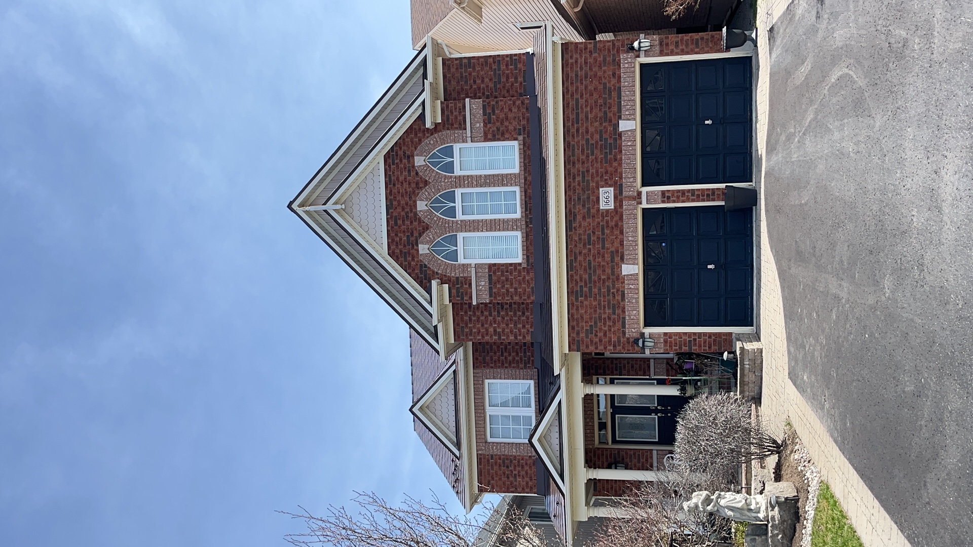 Two-storey brick Colonial home in Oshawa with Interlock aluminum slate roof in Colonial Brown, featuring multi-gable roofline and double navy garage doors.