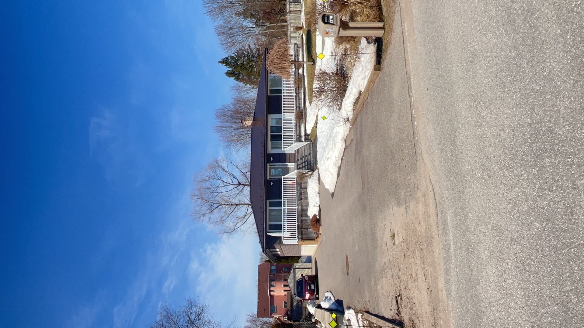 Single-storey ranch home in Innisfil ON with Interlock Colonial Brown aluminum slate metal roof, white front porch railing, and chimney, photographed in winter.