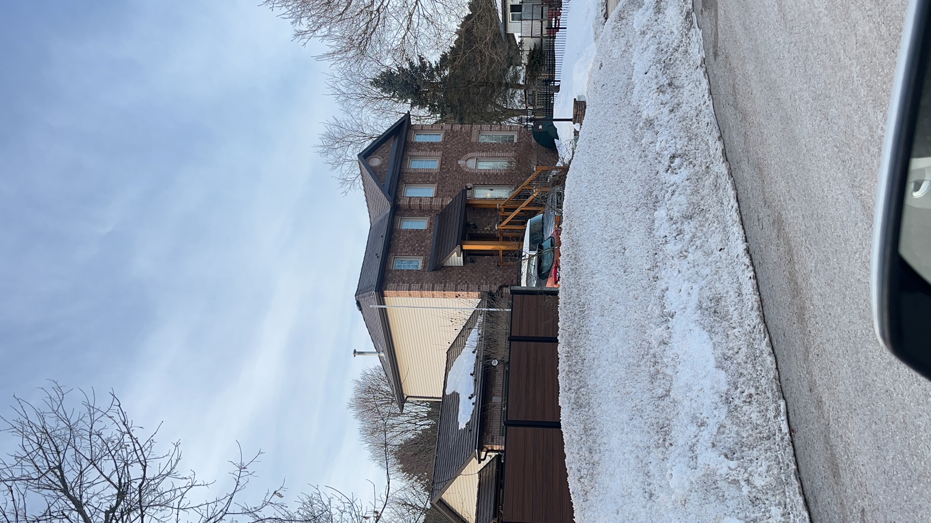 Two-storey brick Colonial home in Angus ON with Interlock Colonial Brown slate metal roof, multi-hip profile, viewed from street in winter.