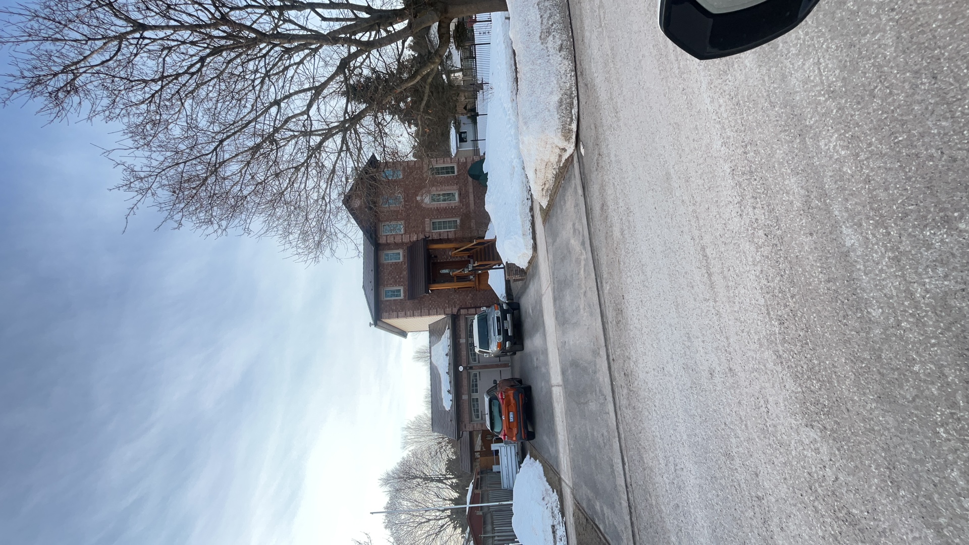 Two-storey brick Colonial home in Angus ON with Interlock Colonial Brown slate metal roofing, viewed from across a snow-covered street in winter.