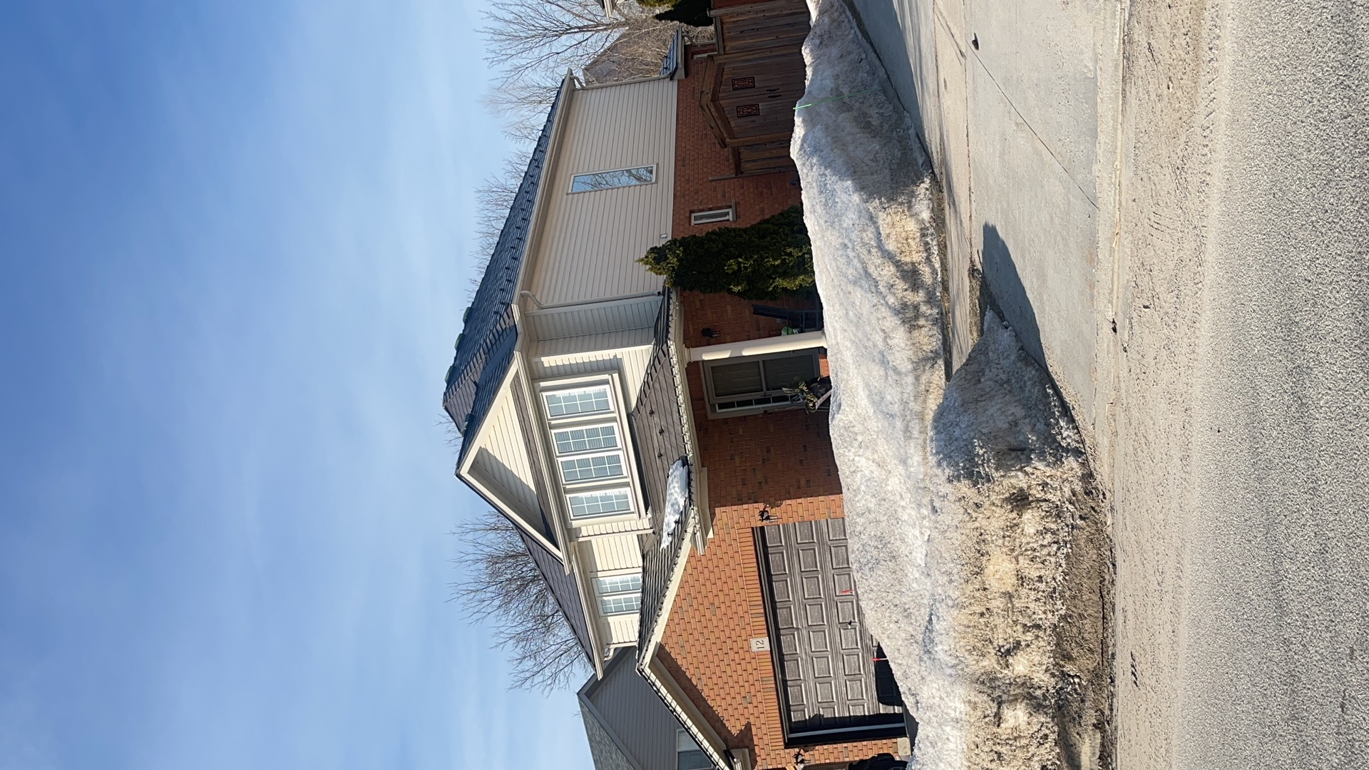 Two-storey brick home in Collingwood ON with Interlock Tudor Brown aluminum slate metal roofing on a multi-hip complex roof under clear winter sky.