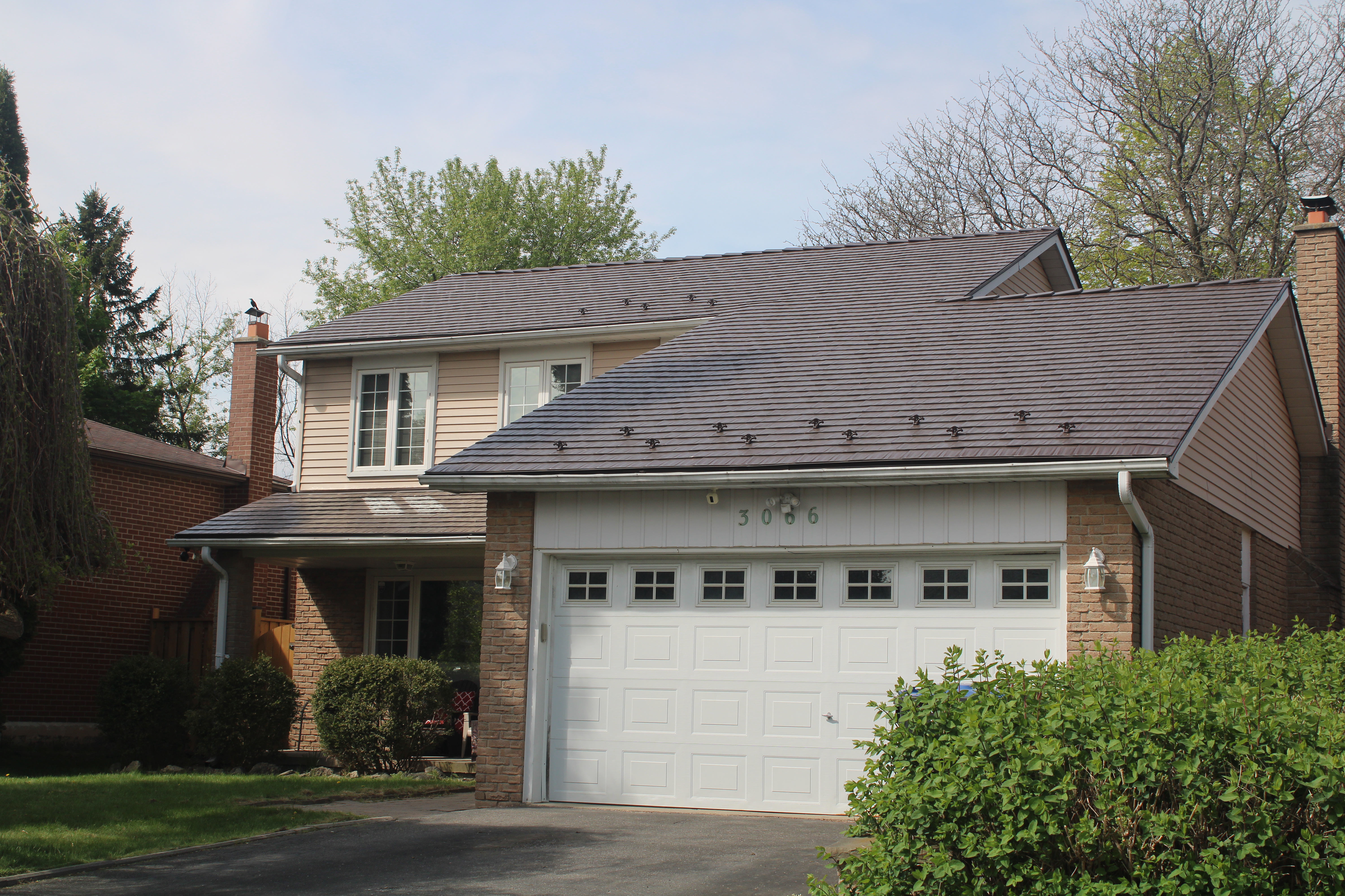 Two-storey suburban home in Mississauga with Interlock Colonial Brown cedar shingle aluminum metal roof, snow guards, double garage, and brick facade.