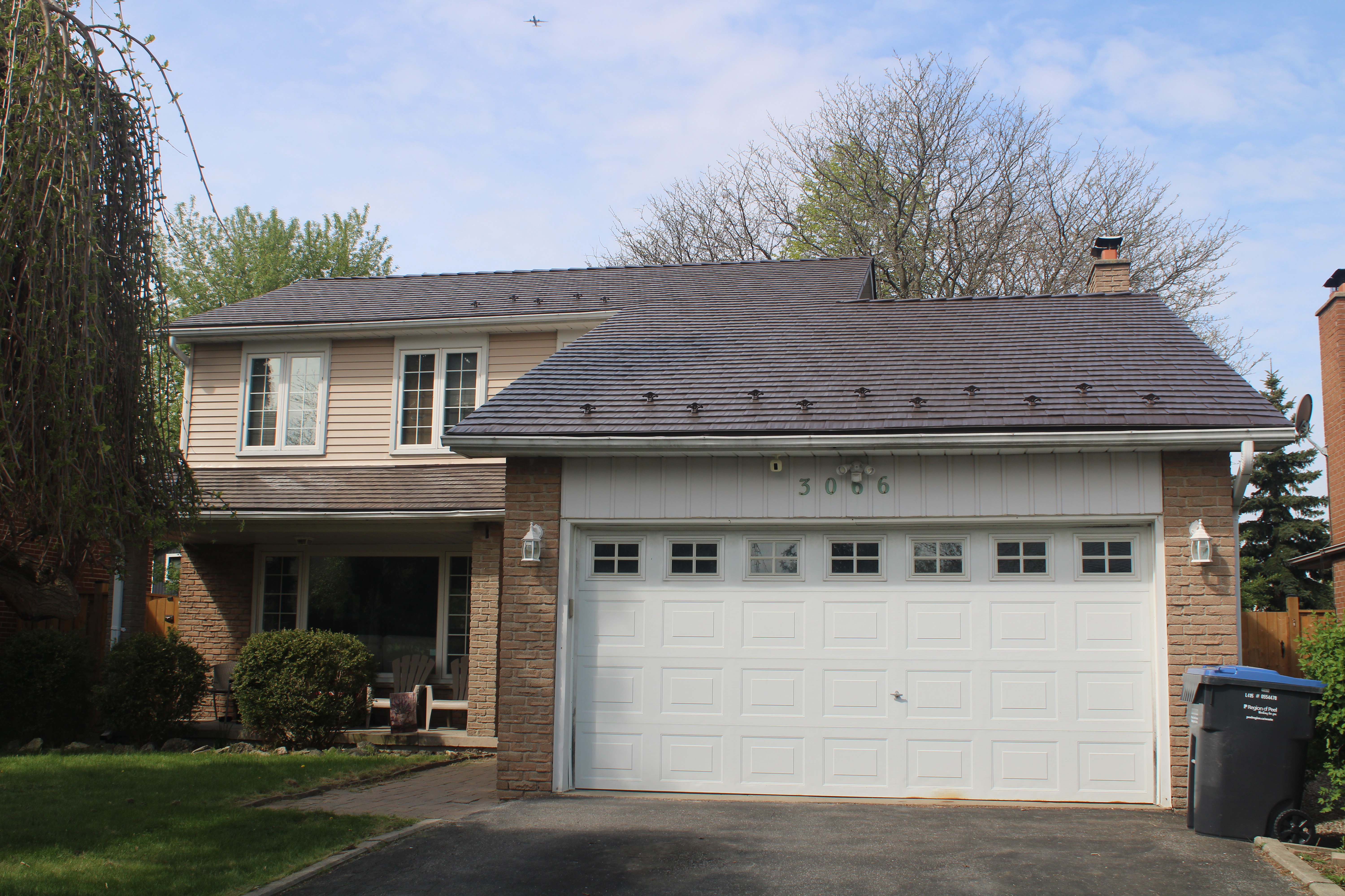 Two-storey Colonial-style home in Mississauga with Interlock aluminum cedar-shingle metal roofing in Colonial Brown, featuring snow guards and a brick chimney.