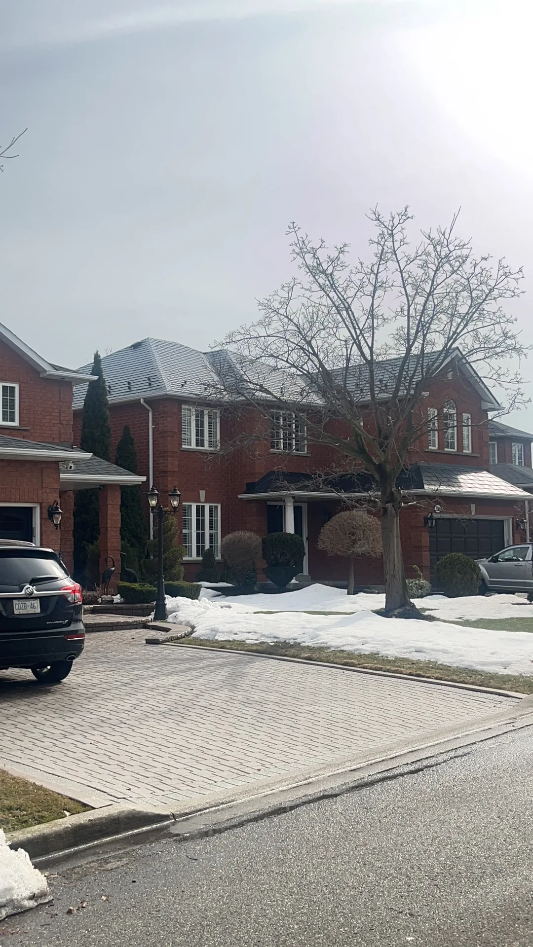 Black Interlock Slate aluminum roof on a red two-storey home with dormers among tall pines, Mississauga, Ontario