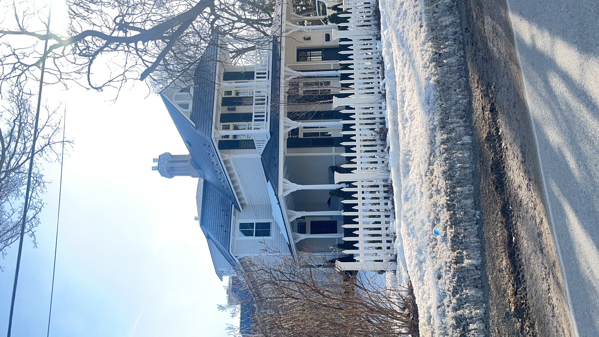 Victorian two-storey home in Collingwood ON with deep charcoal Interlock aluminum slate roof, wrap-around porch, white picket fence, and chimney in winter.
