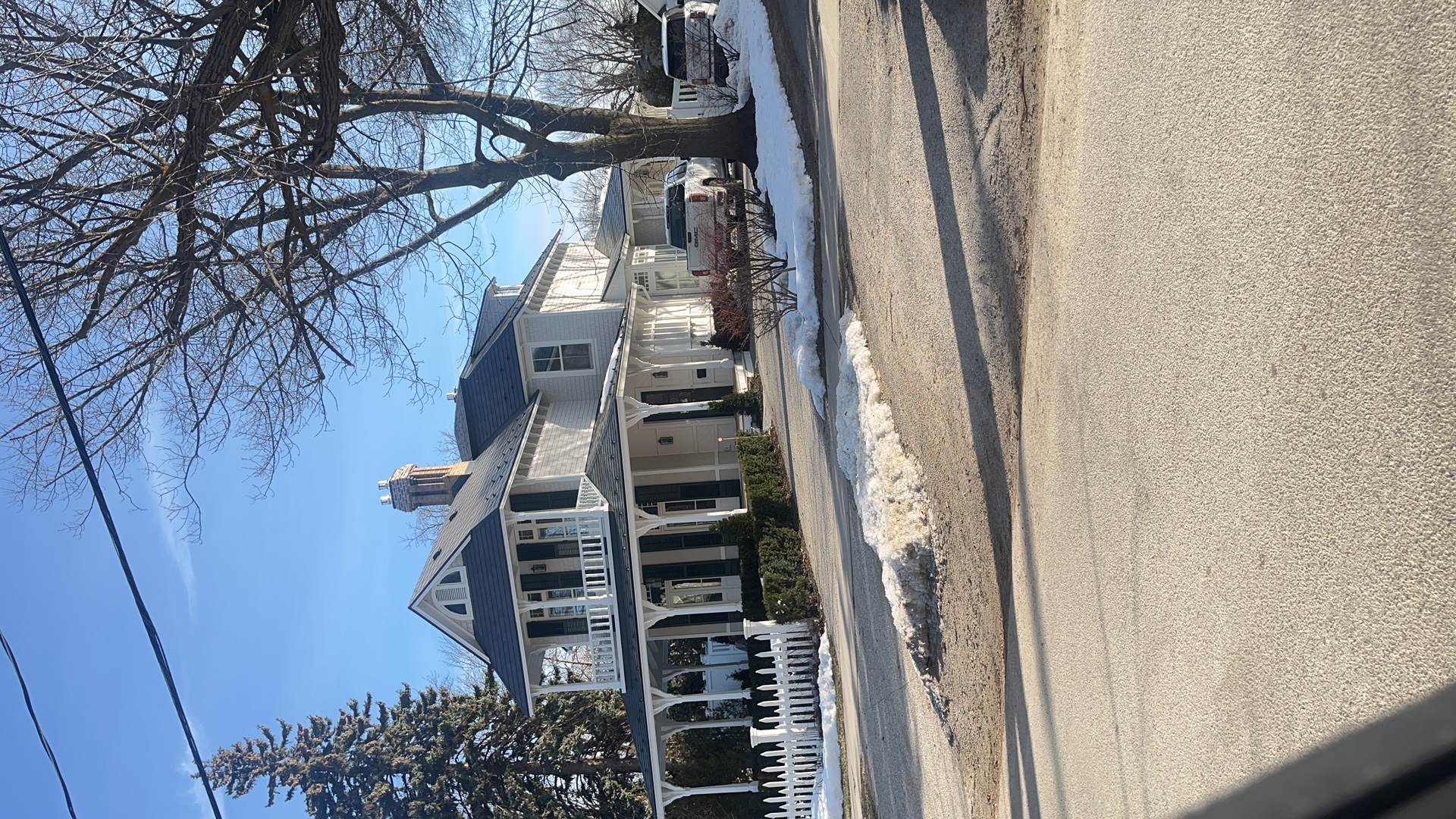 Victorian home in Collingwood ON with deep charcoal Interlock aluminum slate roof, wrap-around porch, dormers, and brick chimney in winter.
