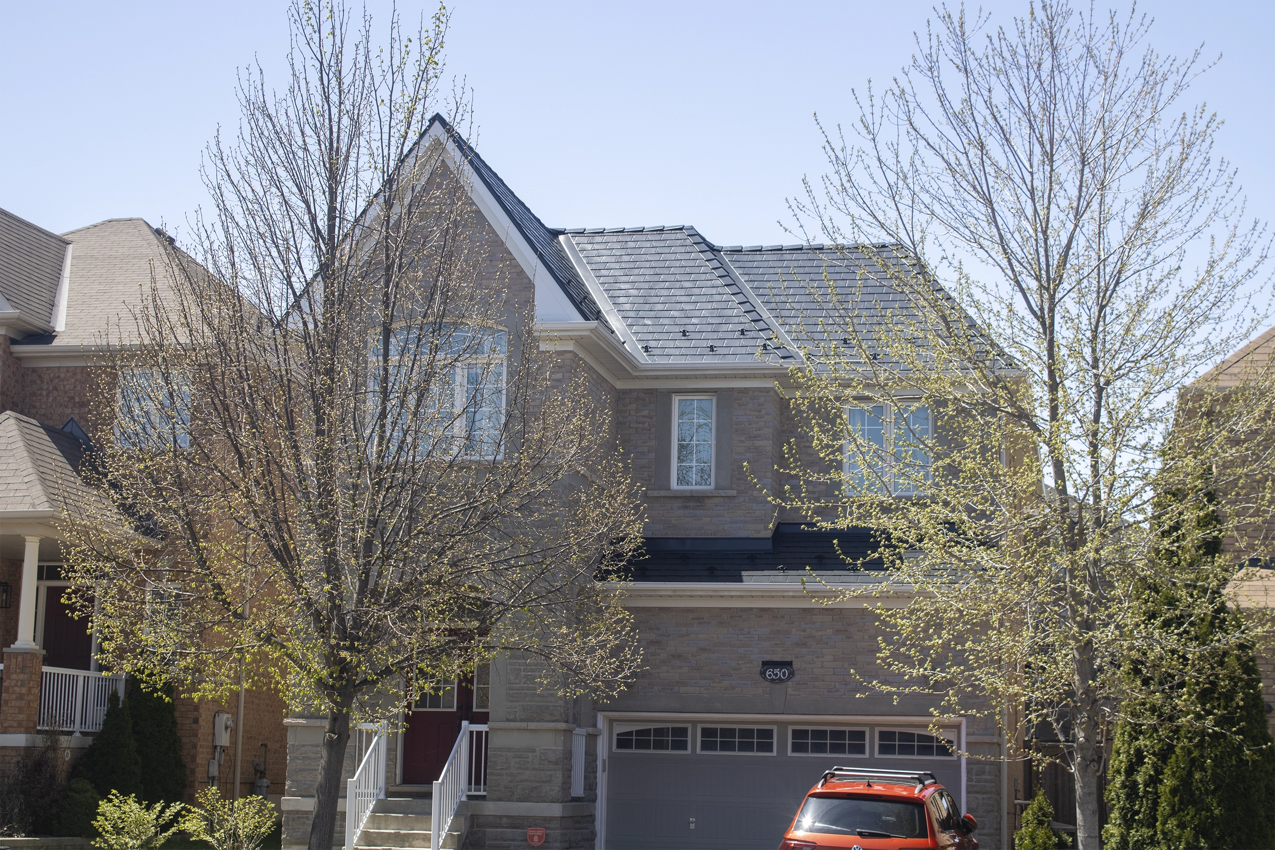 Two-storey brick home in Vaughan, ON featuring a dark charcoal Interlock aluminum slate metal roof with dormers, valleys, and snow guards.