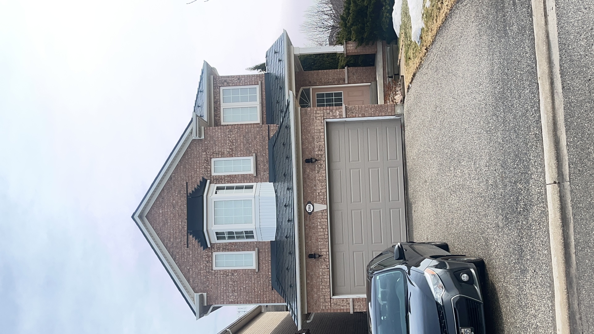 Two-storey brick home in Mississauga with Interlock deep charcoal aluminum slate metal roofing covering a multi-plane complex roof with bay window.