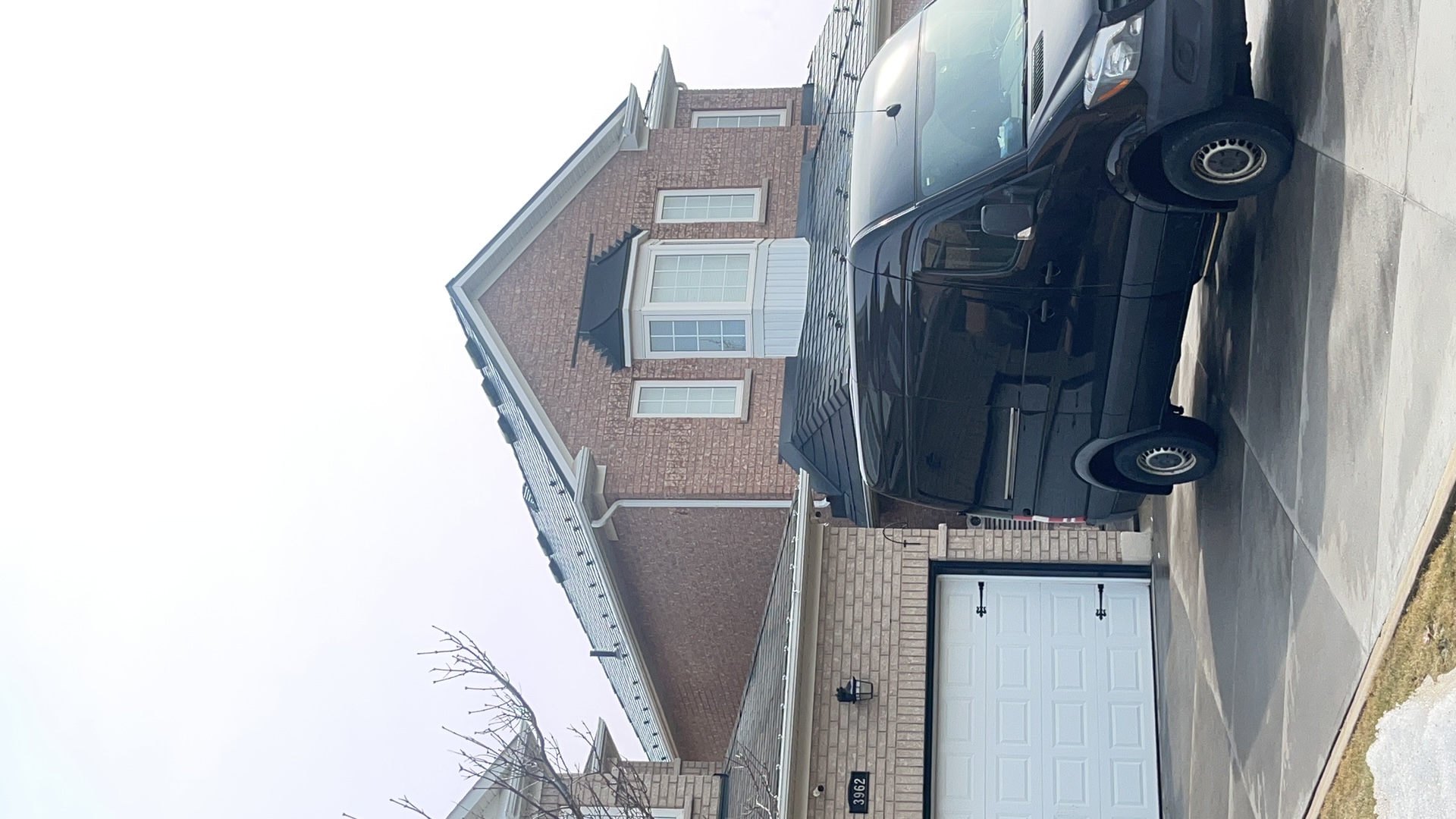 Two-storey brick home in Mississauga with Interlock deep charcoal aluminum slate metal roof featuring a front dormer and complex hip-gable profile.