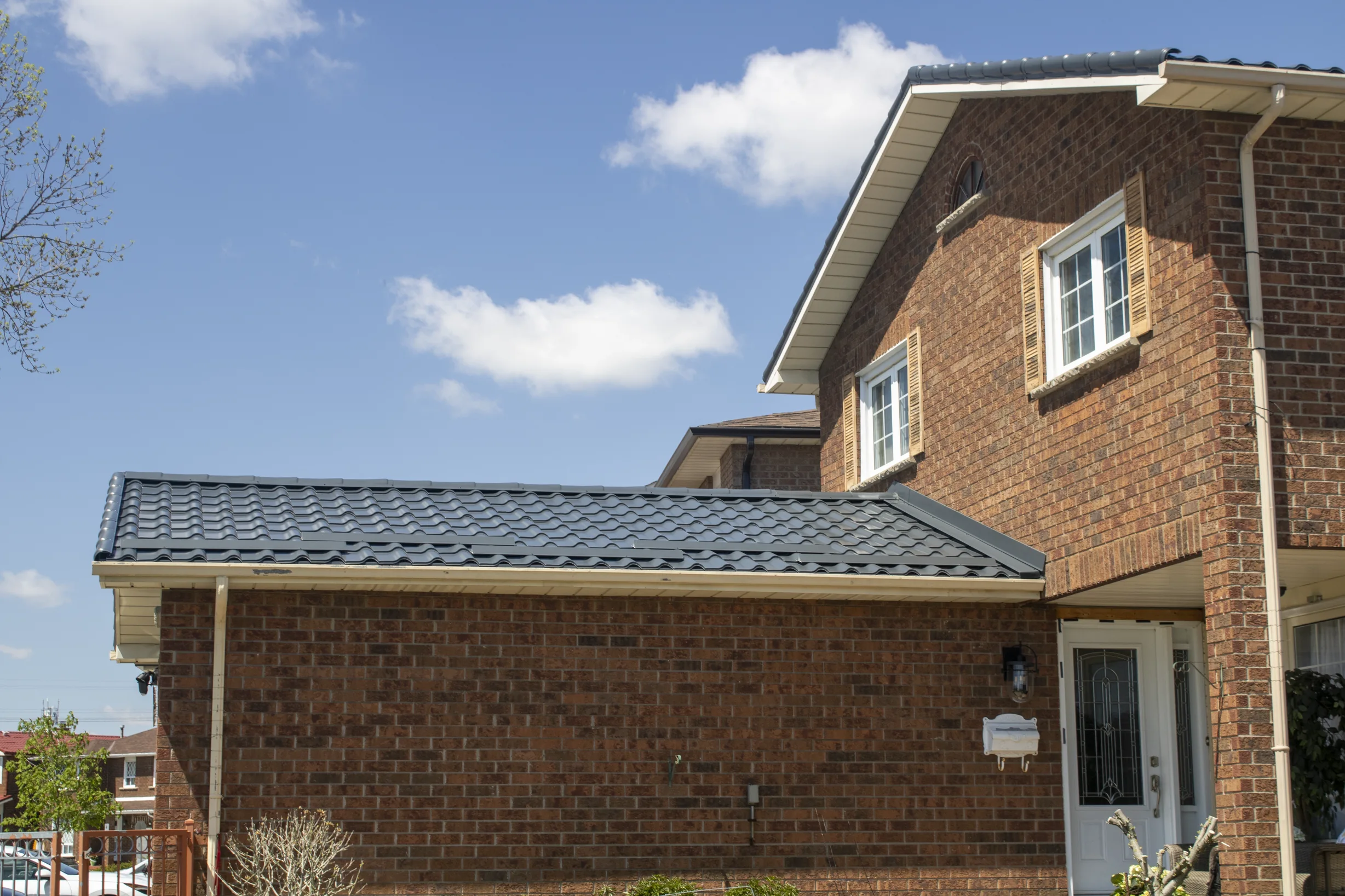 Deep Charcoal Interlock Tile aluminum roof on a two-storey brick home with dormers in a suburban, Etobicoke, Ontario