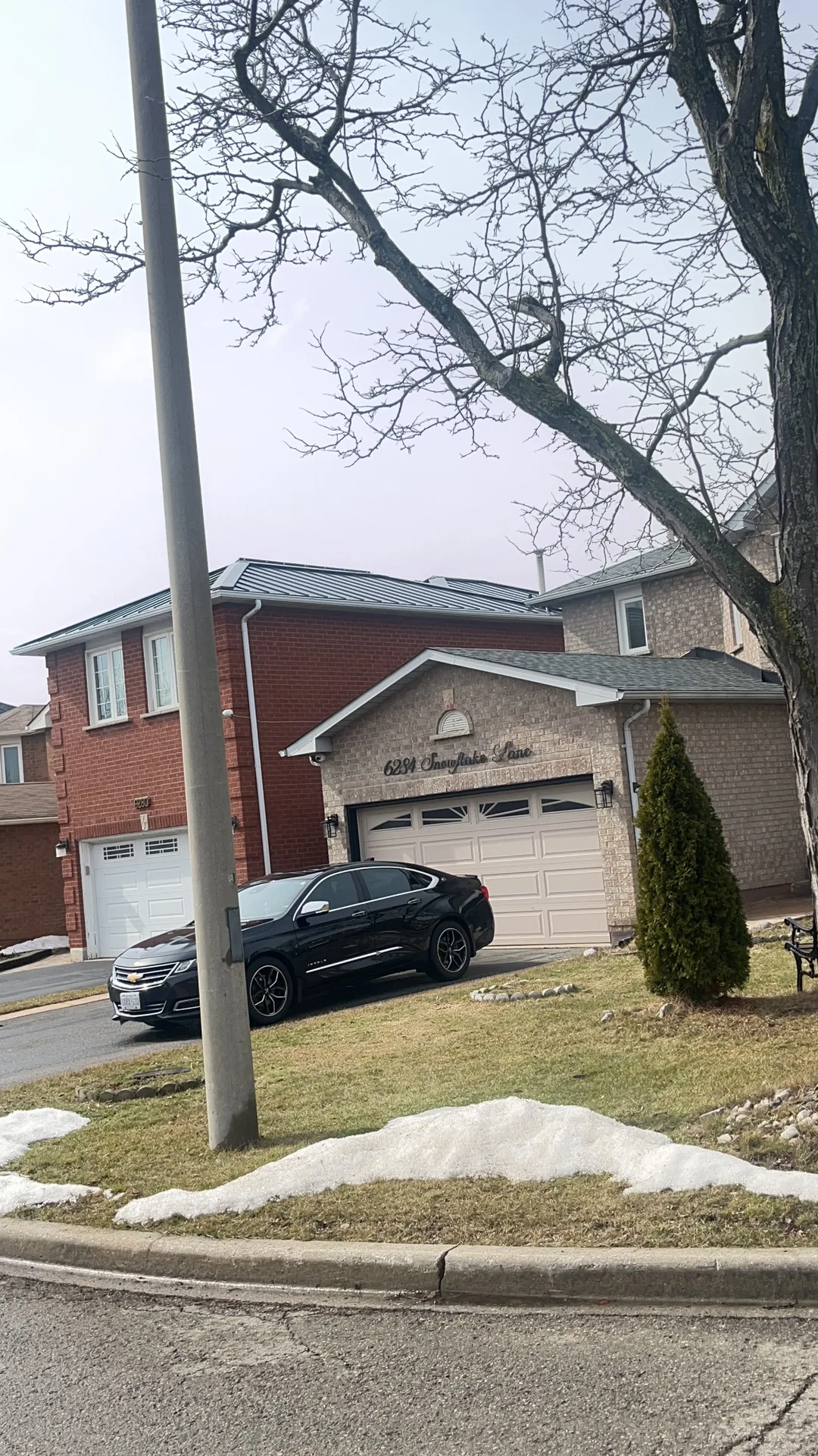 Black Interlock Standing Seam aluminum roof on a tan two-storey home with dormers in a suburban, Mississauga, Ontario