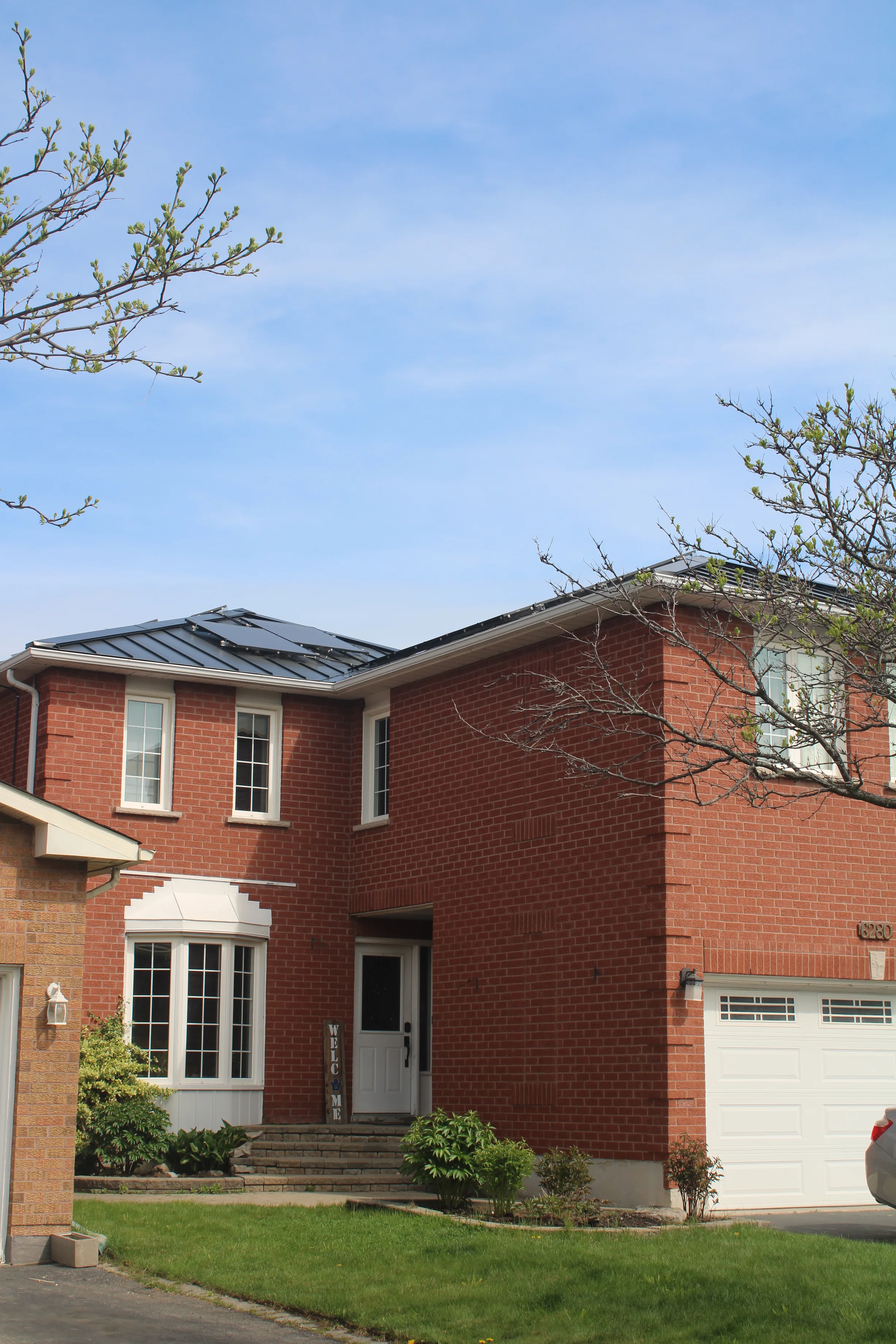 Black Interlock Standing Seam aluminum roof on a red brick two-storey colonial home with dormers, Mississauga, Ontario