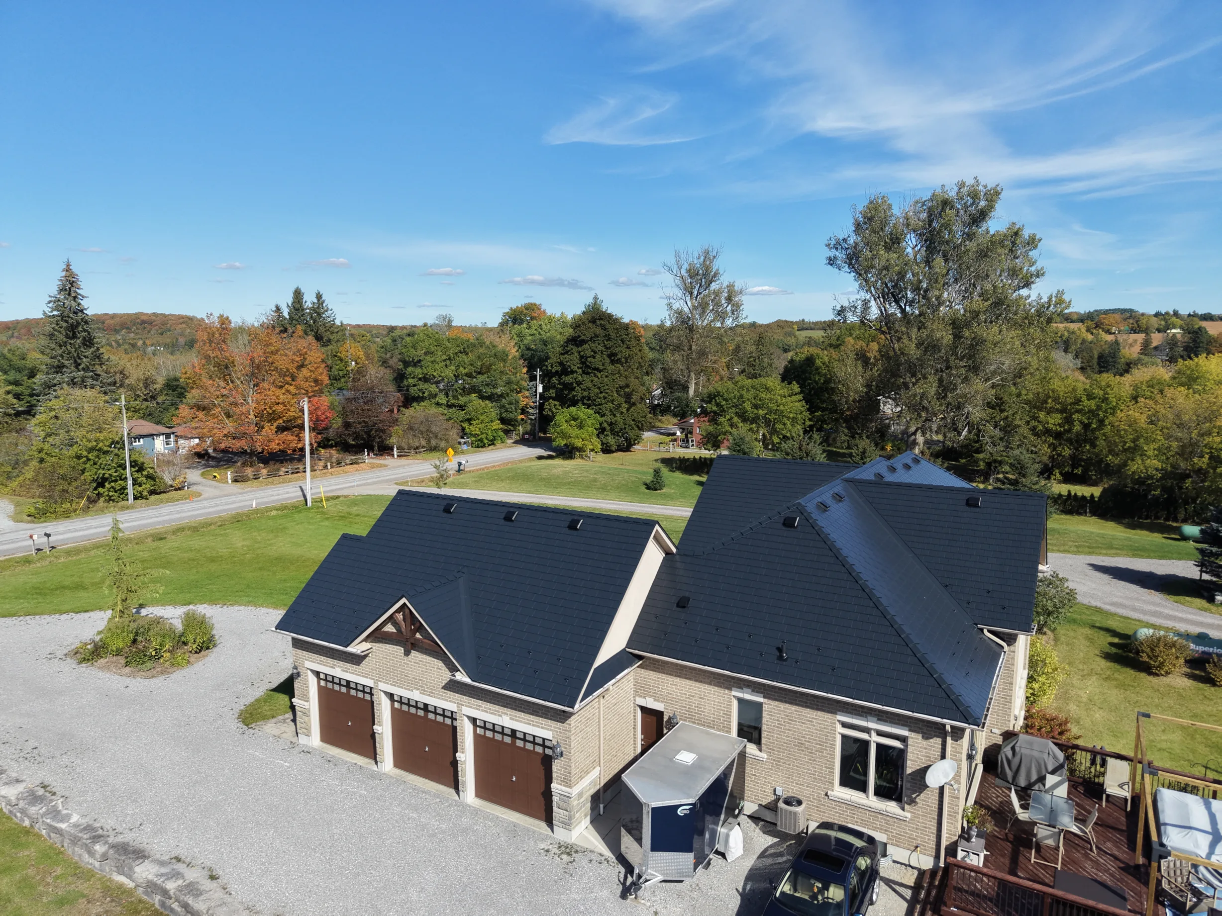 Black Interlock Slate aluminum roof on a tan ranch-style home with a brown deck in a rural setting, Blackstock, Ontario