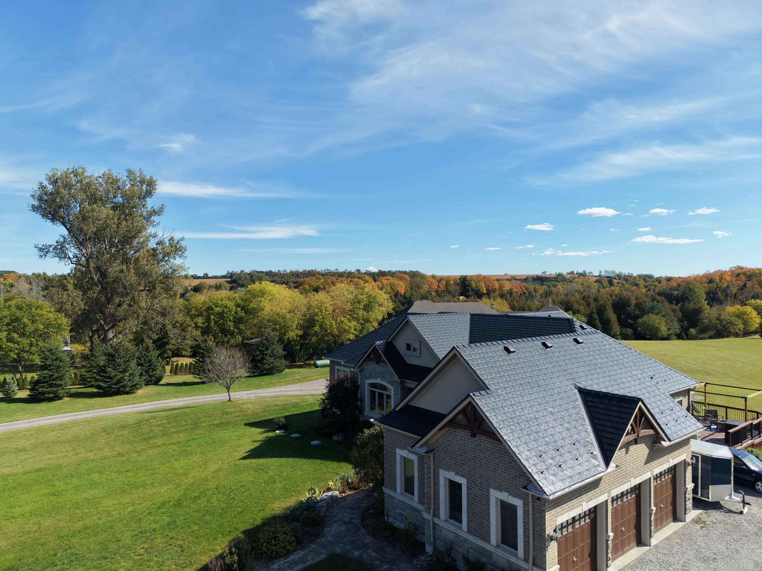 Black Interlock Slate aluminum roof on a modern home with a grey metal roof in a forested rural, Blackstock, Ontario