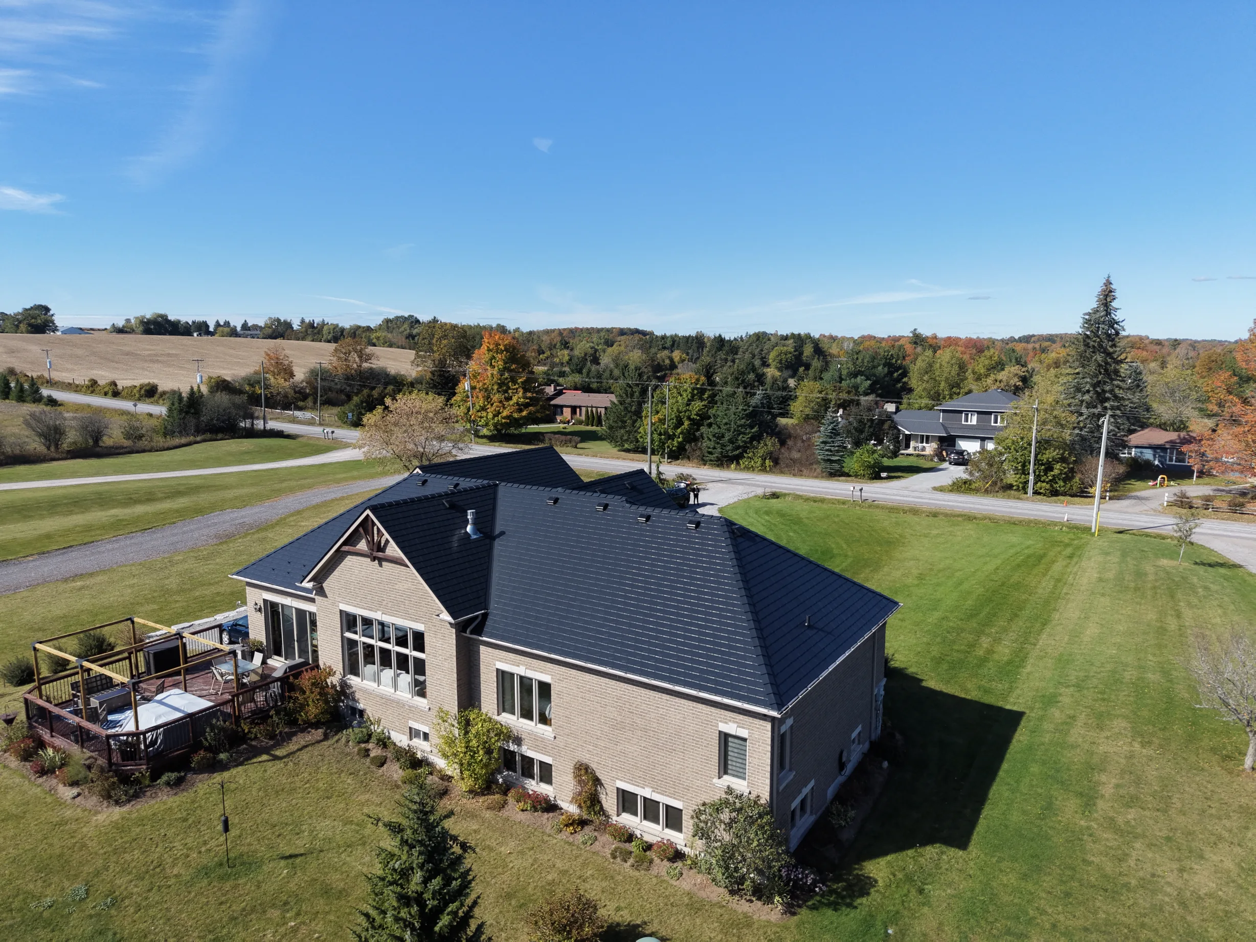 Black Interlock Slate aluminum roof on a beige single-storey home with a black metal roof in a, Blackstock, Ontario