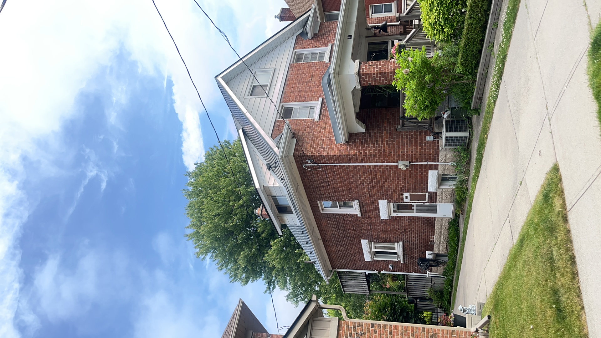 Two-storey red brick home in Kitchener ON featuring Interlock deep charcoal aluminum slate metal roofing with dormer and covered front porch.