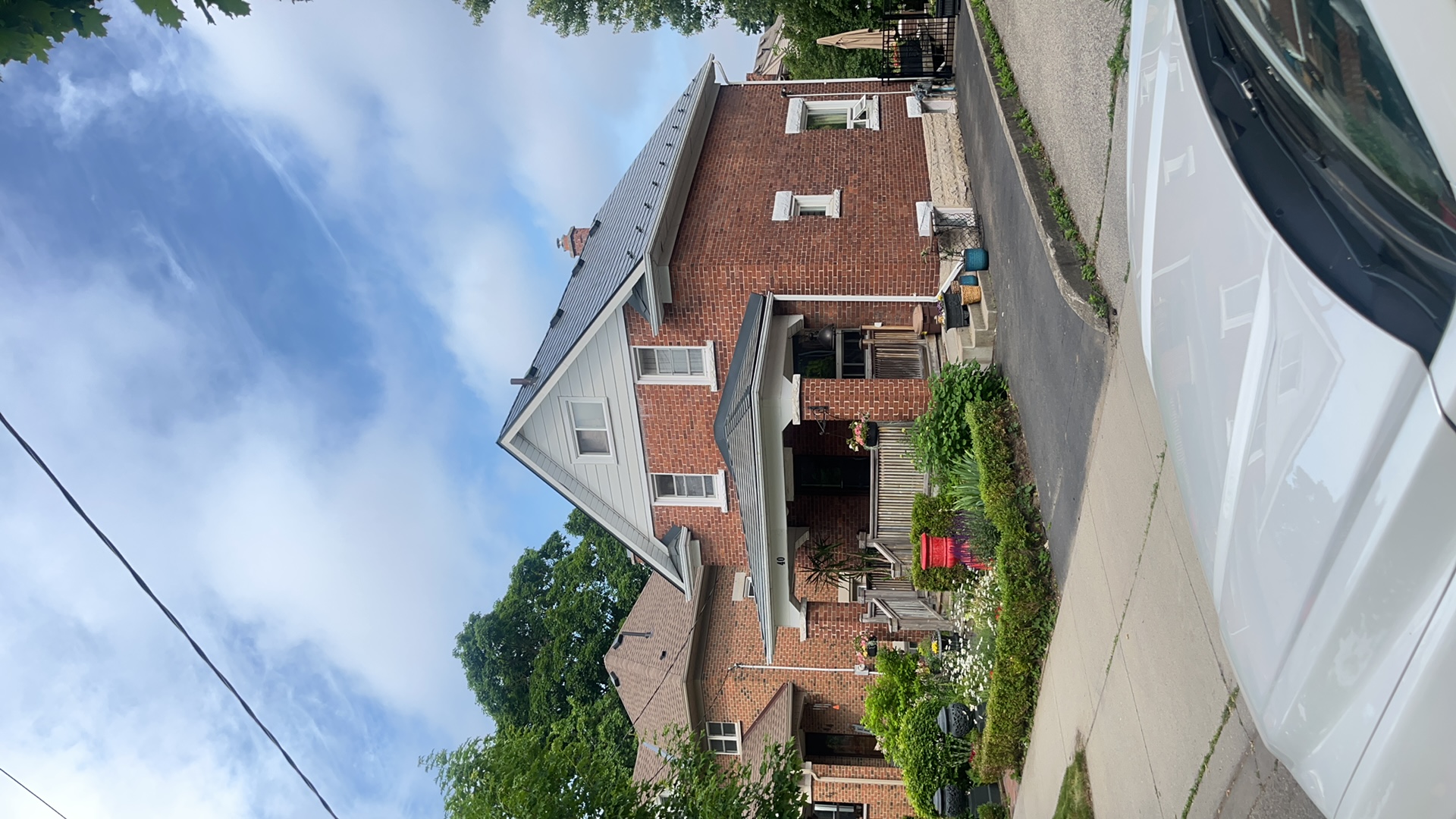 Two-storey brick Craftsman home in Kitchener ON with a steep deep charcoal Interlock aluminum slate metal roof and covered front porch.