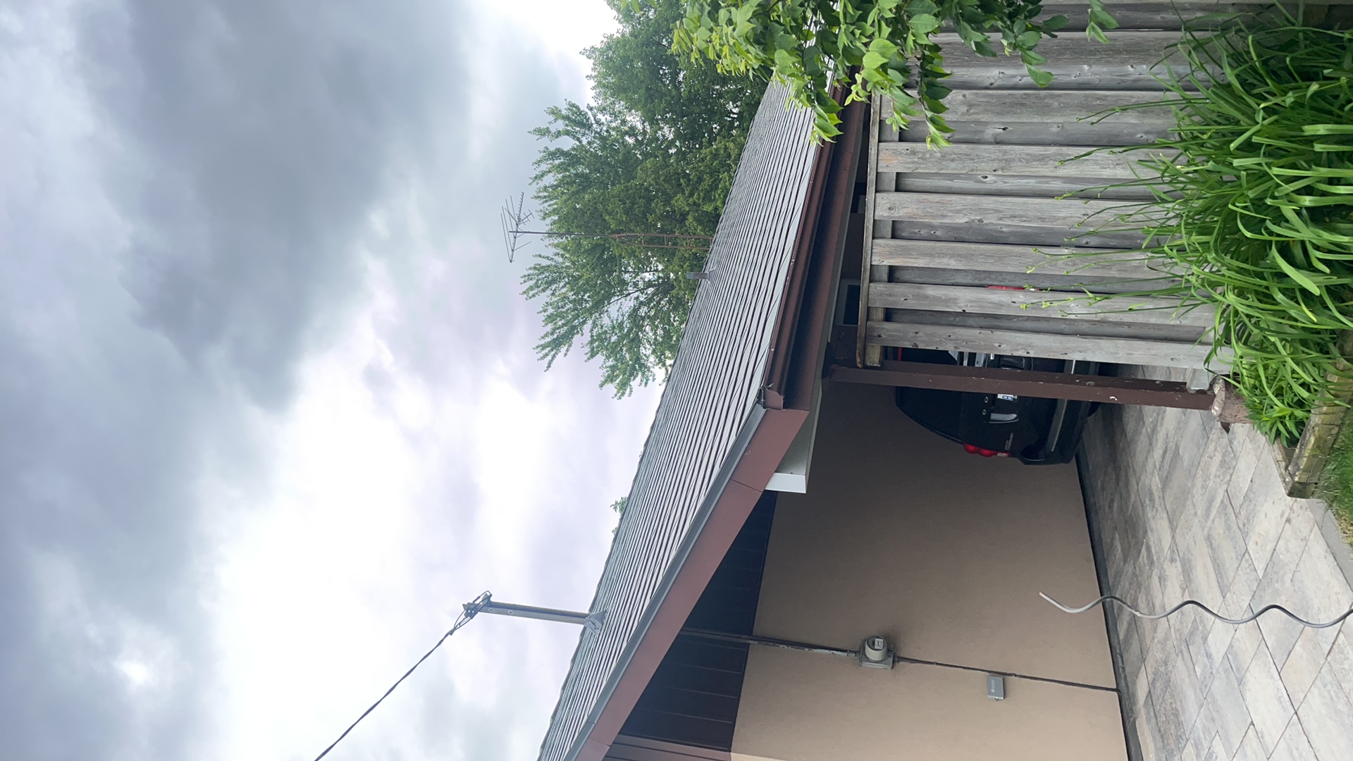 Low-slope gable ranch home in Scarborough with Interlock Musket Grey aluminum slate metal roofing, viewed from front-right under overcast skies.