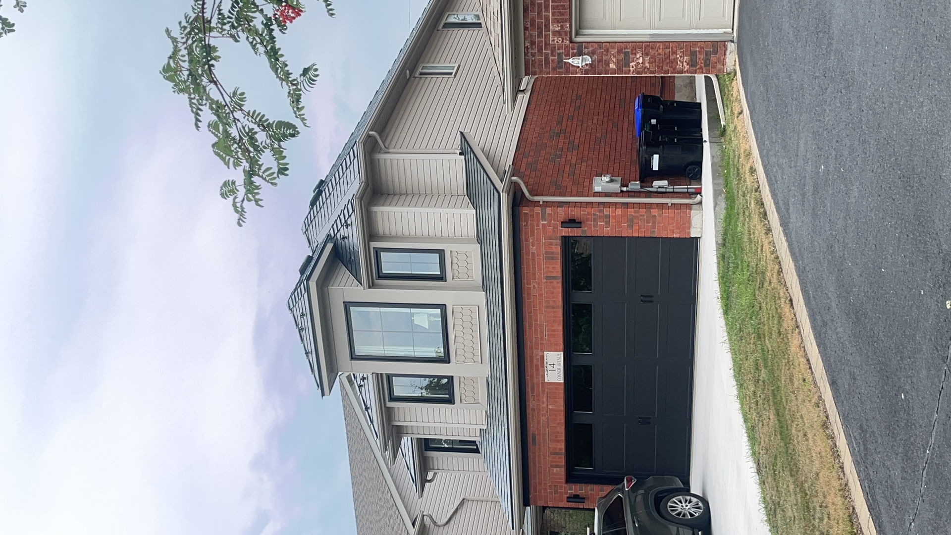 Two-storey brick home in Collingwood ON with Interlock deep charcoal aluminum slate metal roofing featuring a prominent front dormer and multi-hip roof.