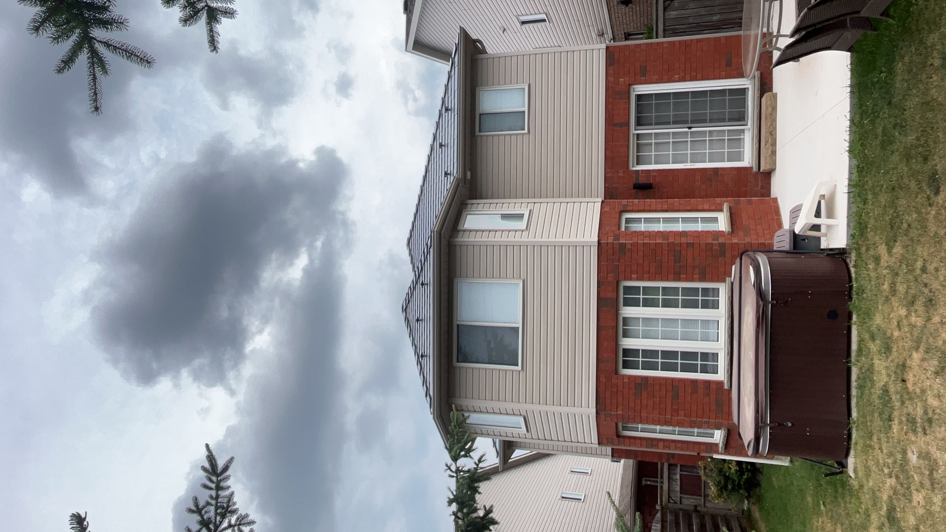 Rear elevation of a 2-storey brick-and-vinyl home in Collingwood, ON featuring an Interlock deep charcoal aluminum slate metal roof on a multi-hip structure.