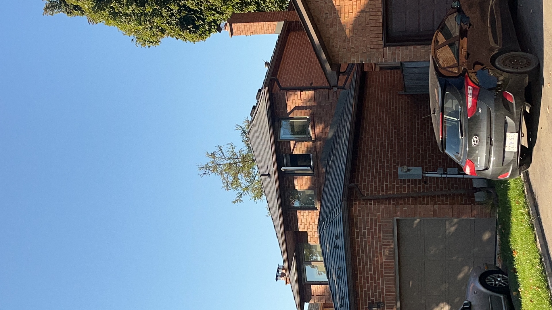 Two-storey red brick home in Markham ON with Interlock Musket Grey aluminum slate multi-hip roof, two chimneys, and attached garage.