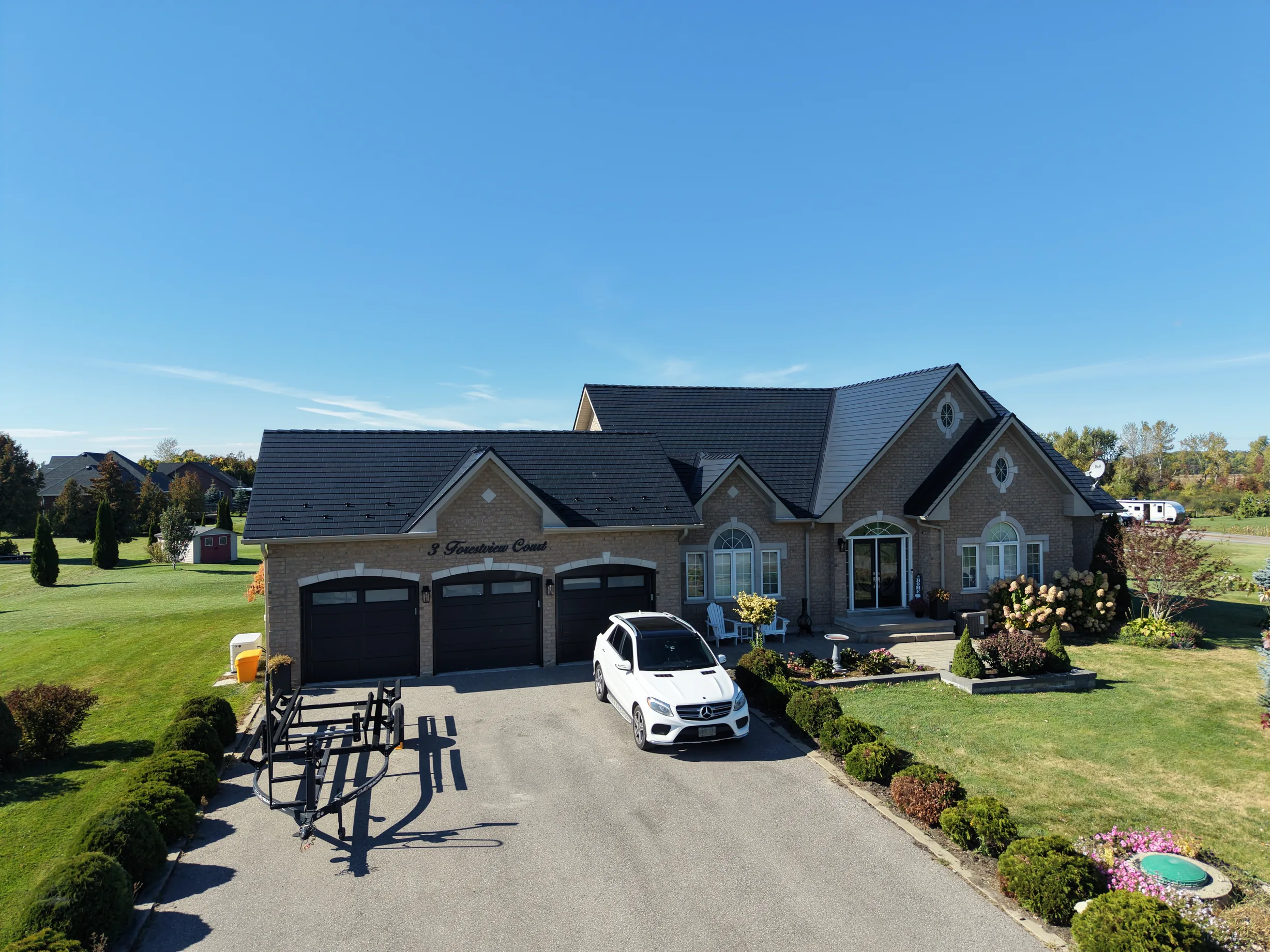 Black Interlock Slate aluminum roof on a brown ranch home with a metal roof among trees, Kawartha Lakes, Ontario