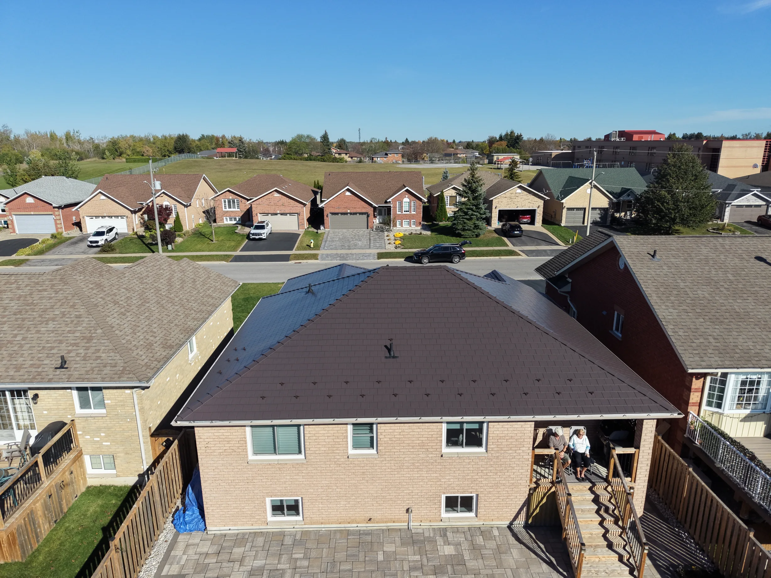 Tudor Brown Interlock Slate aluminum roof on a tan single-family home with a brown metal roof in rural, Lindsay, Ontario