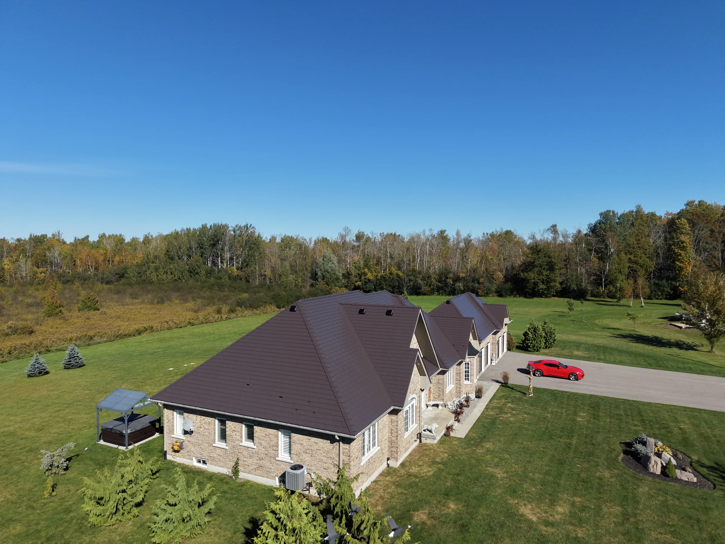 Tudor Brown Interlock Slate aluminum roof on a brown single-storey home with dormers in a forest clearing, Kawartha Lakes, Ontario