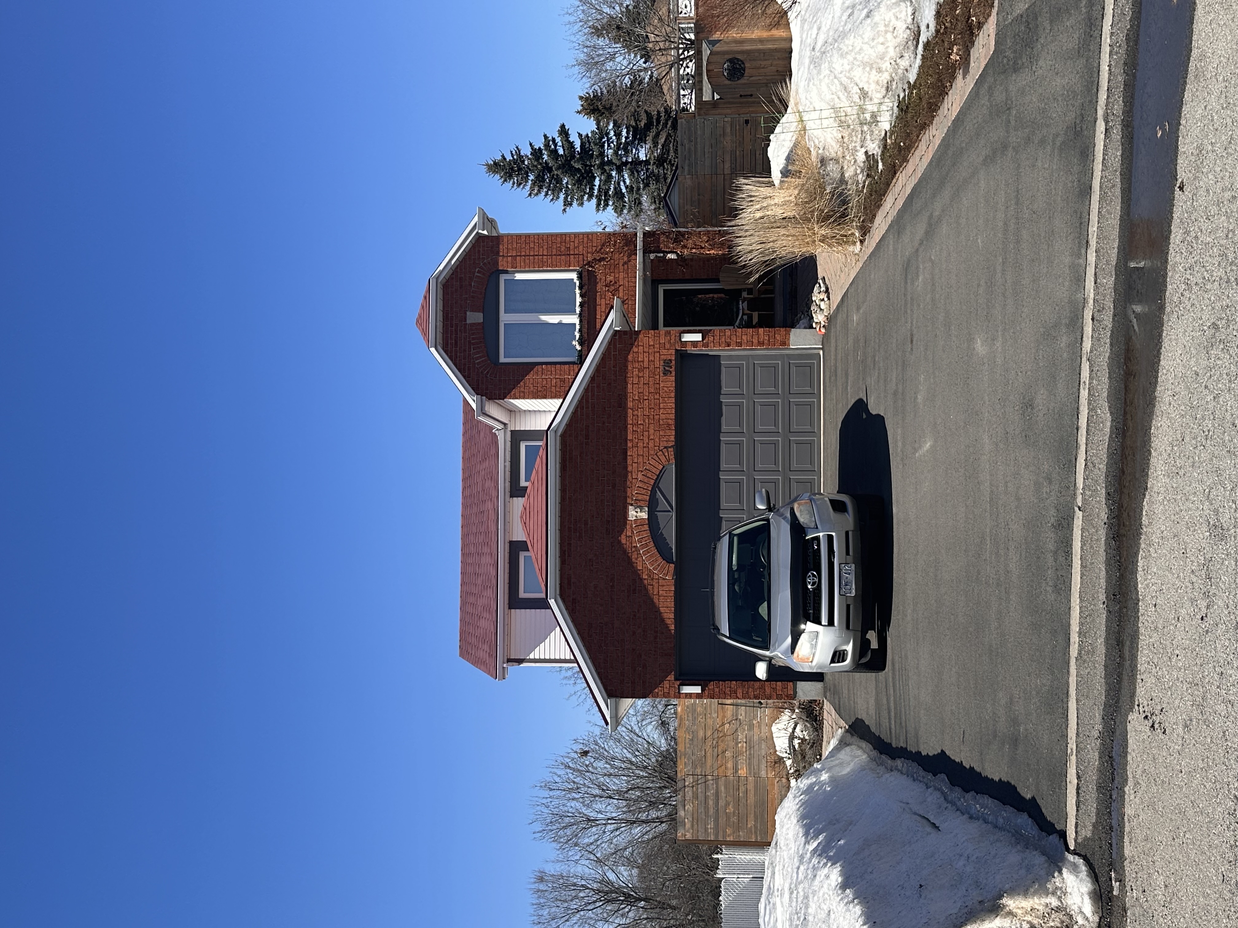 Two-storey red-brick suburban home in Orleans ON with Interlock Tile Red aluminum shingle roof, multi-hip profile, and attached single-car garage.