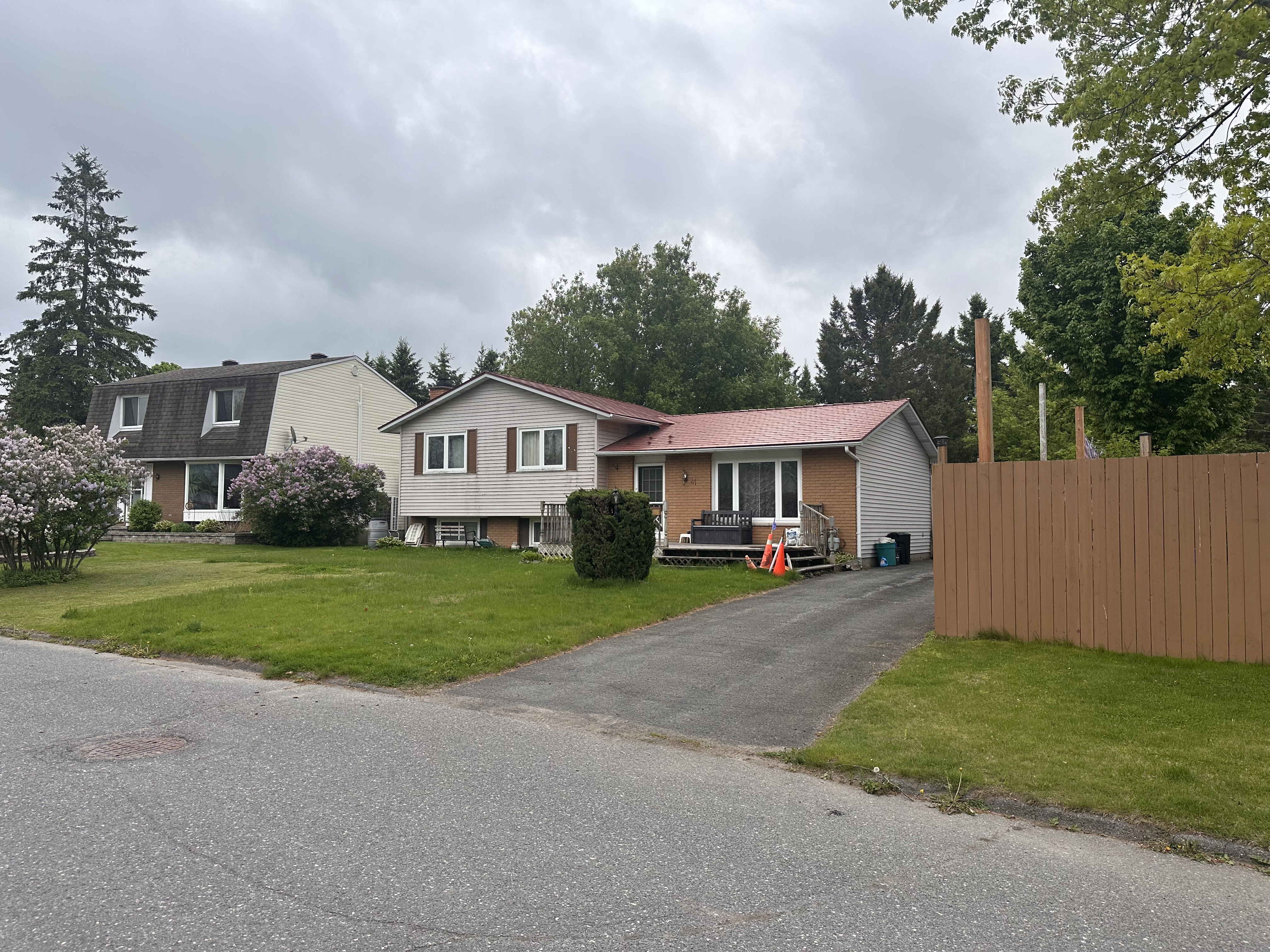 Street view of a 1.5-storey ranch-style home in Munster, ON featuring a Tile Red Interlock aluminum shingle metal roof with a simple gable profile.