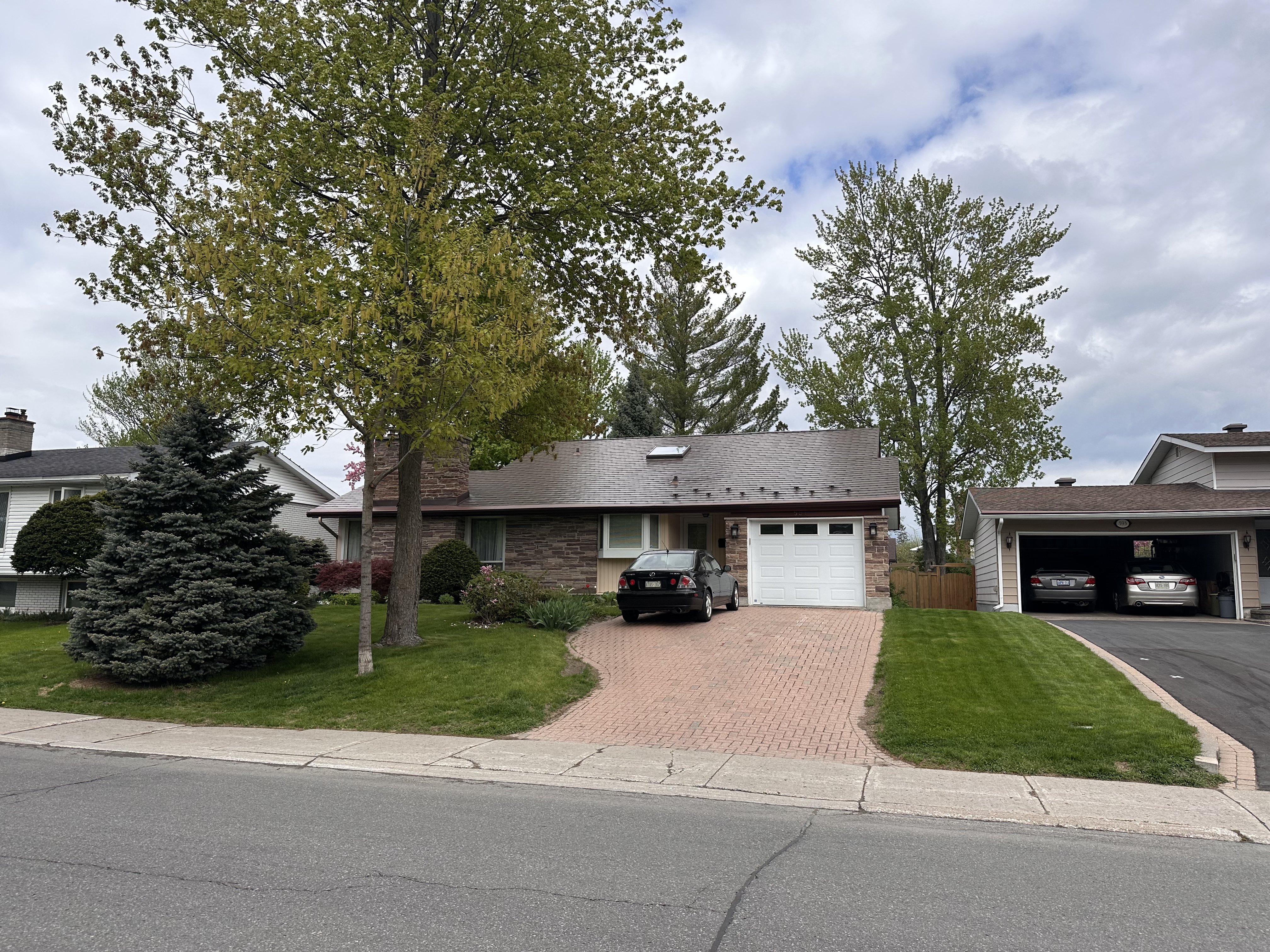 Street view of a ranch-style Ottawa home with Interlock Colonial Brown aluminum shingle roof, skylight, brick facade, and paver driveway.