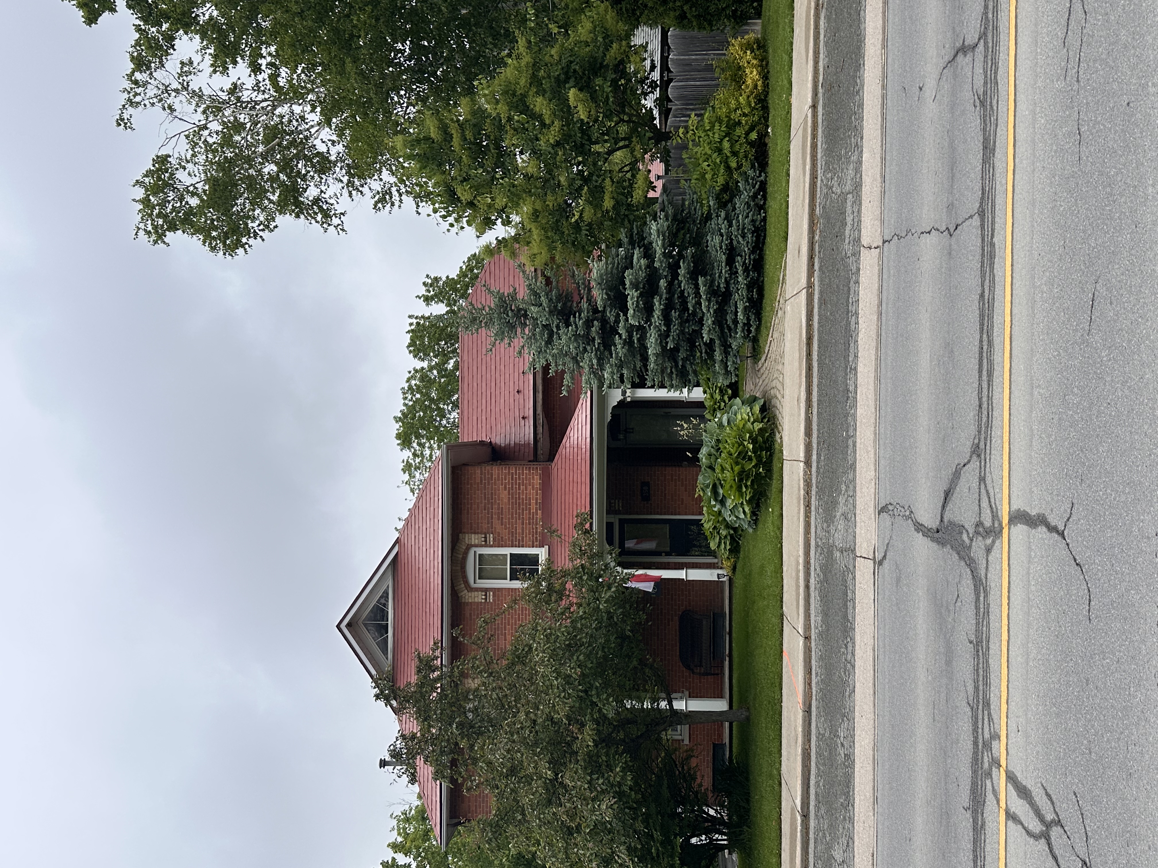 Two-storey Victorian brick home in Almonte, ON with a complex steep Tile Red Interlock aluminum shingle roof featuring a front dormer and wrap-around porch.