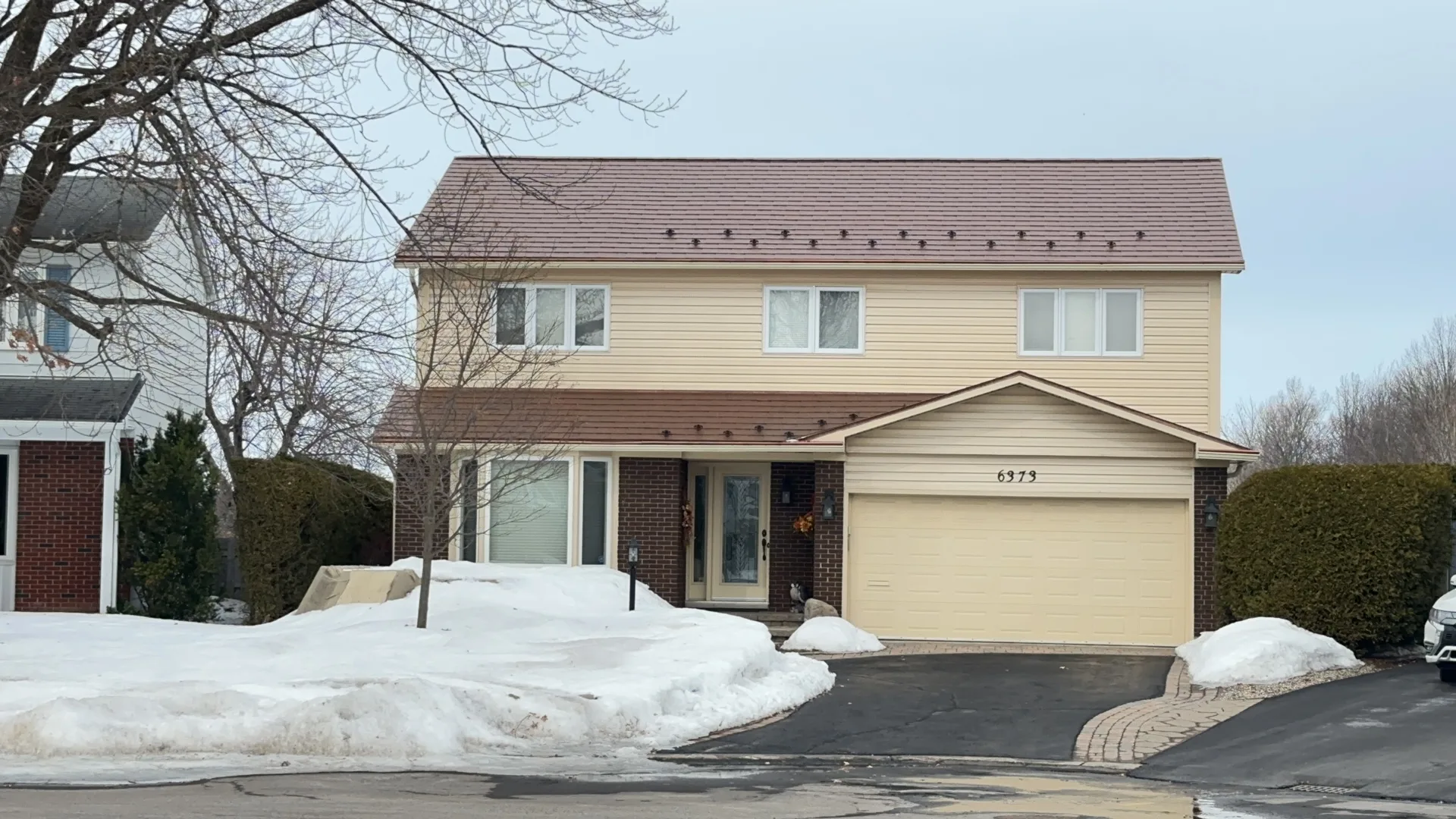 Two-storey colonial-style home in Orleans ON with Interlock aged copper aluminum shingle metal roof, snow guards visible along eaves, winter setting.