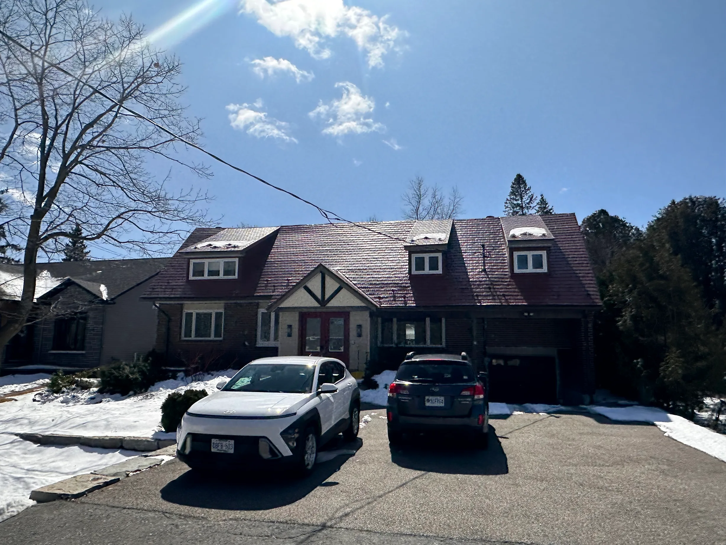 Tile Red Interlock Shingle aluminum roof on a red two-storey home with dormers among tall pines, Stittsville, Ontario