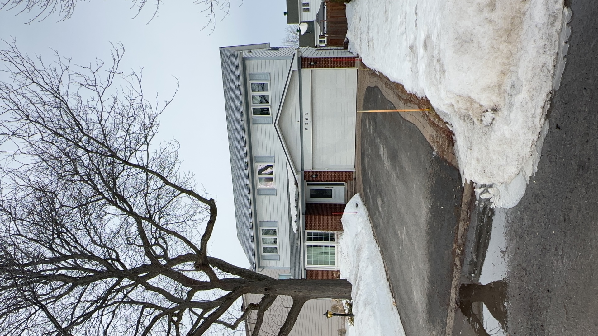 Two-storey colonial-style home in Orleans ON with Interlock charcoal grey aluminum slate metal roofing, brick lower facade, and attached garage.