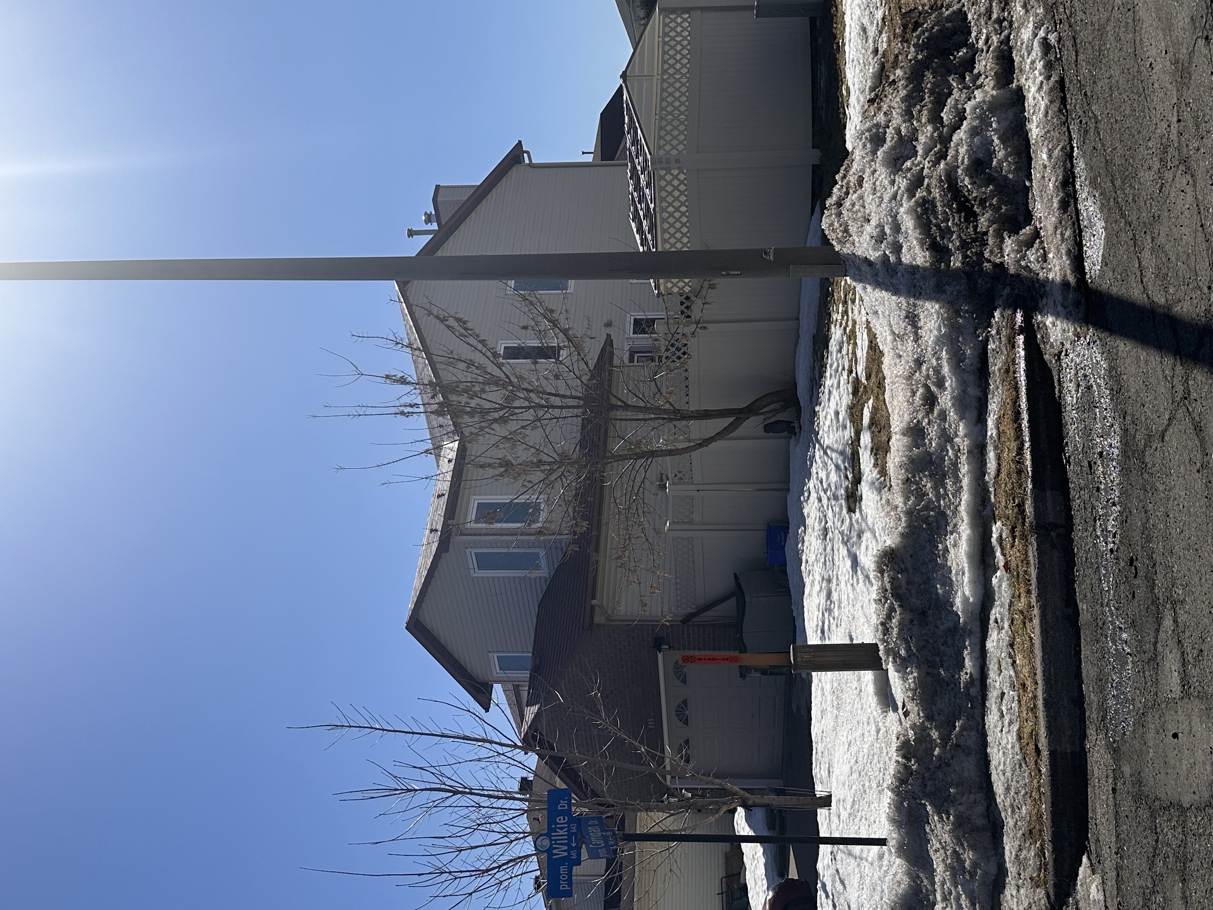 Two-storey suburban colonial home in Orleans ON with Interlock aluminum shingle roofing in Tile Red, viewed from street corner in winter.