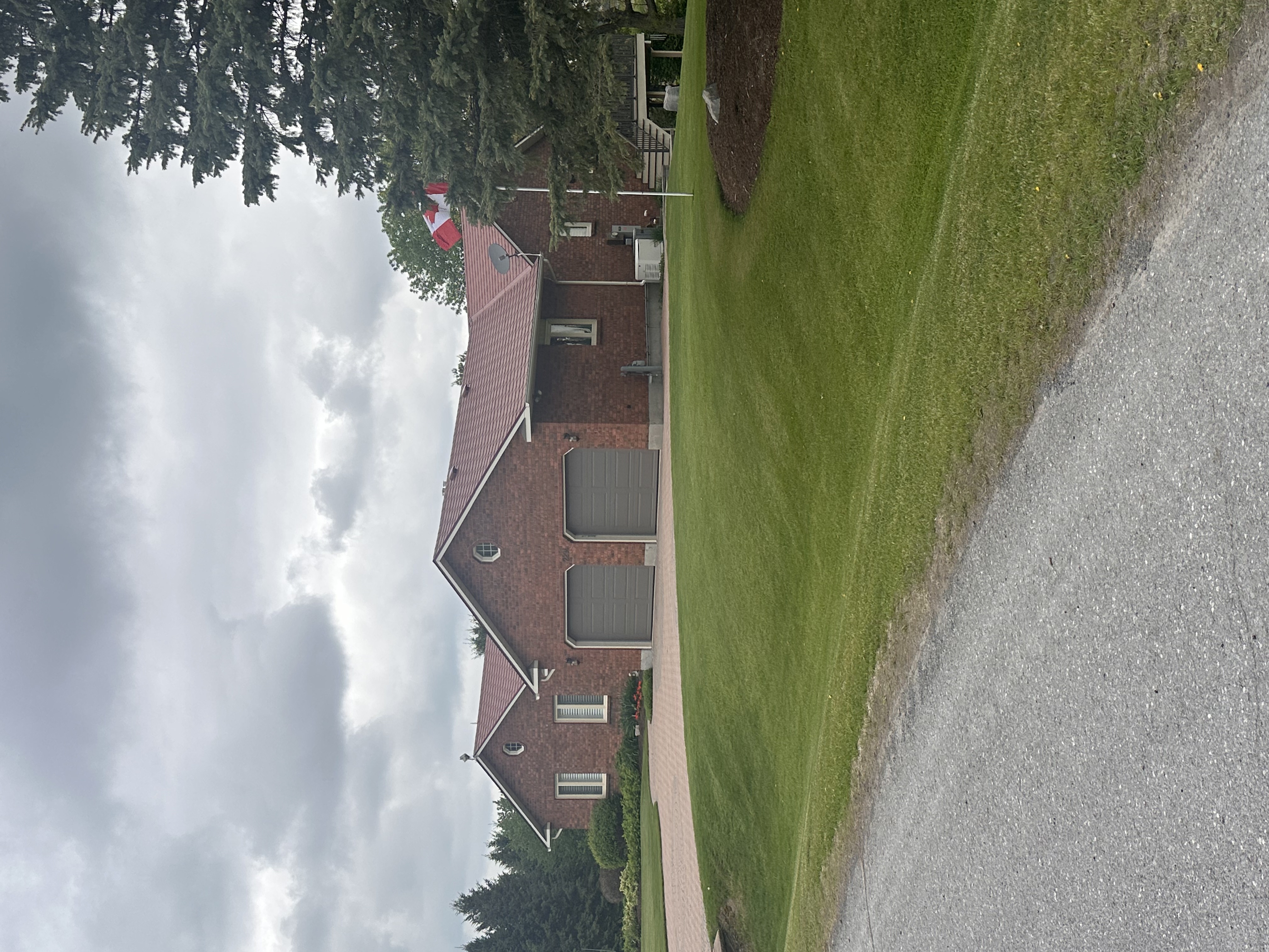Single-storey brick ranch home in North Gower ON with Interlock Tile Red aluminum shingle roof, two-car garage, and manicured lawn.