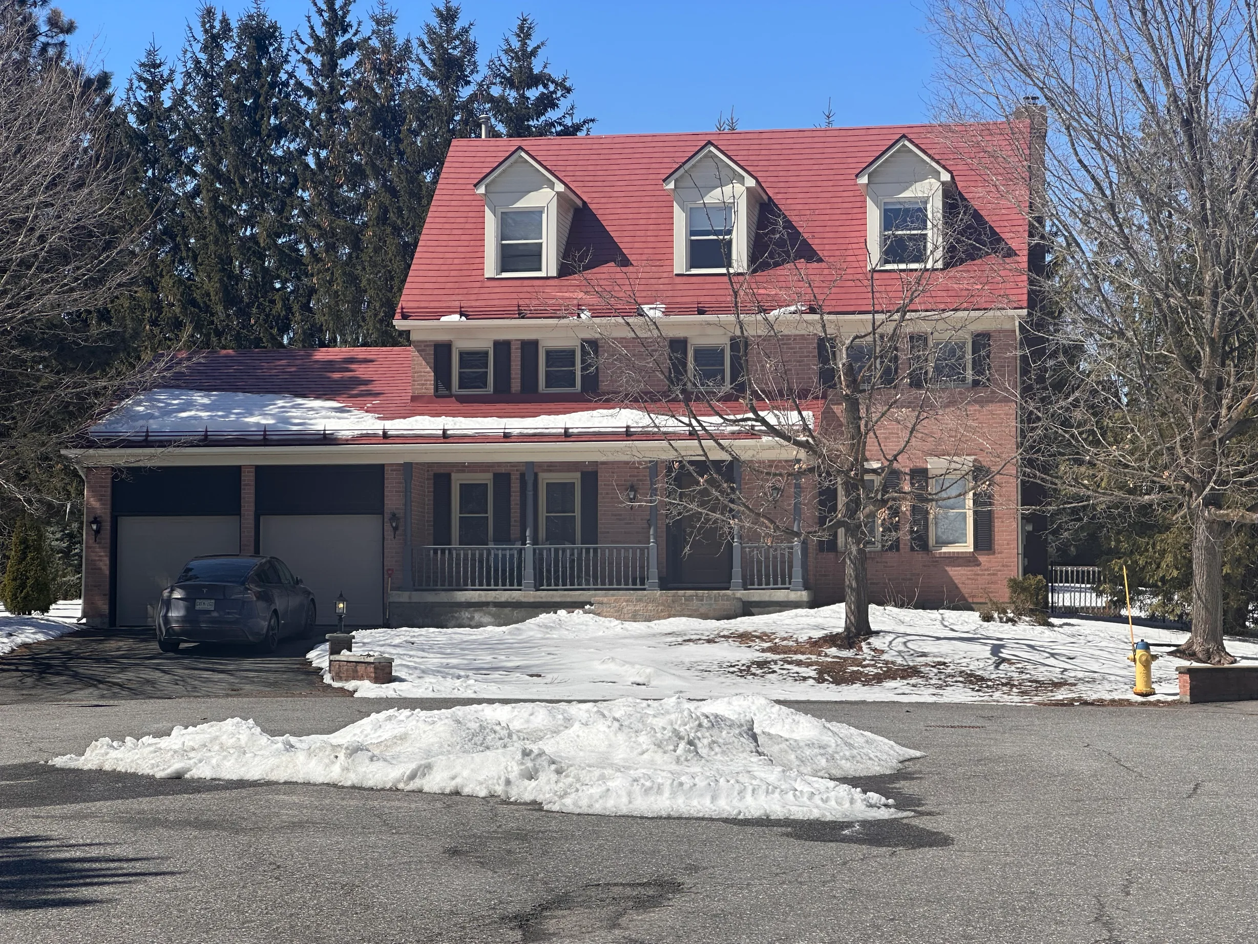 Aged Copper Interlock Shingle aluminum roof on a two-storey red brick home with a metal roof and snow on, Stittsville, Ontario