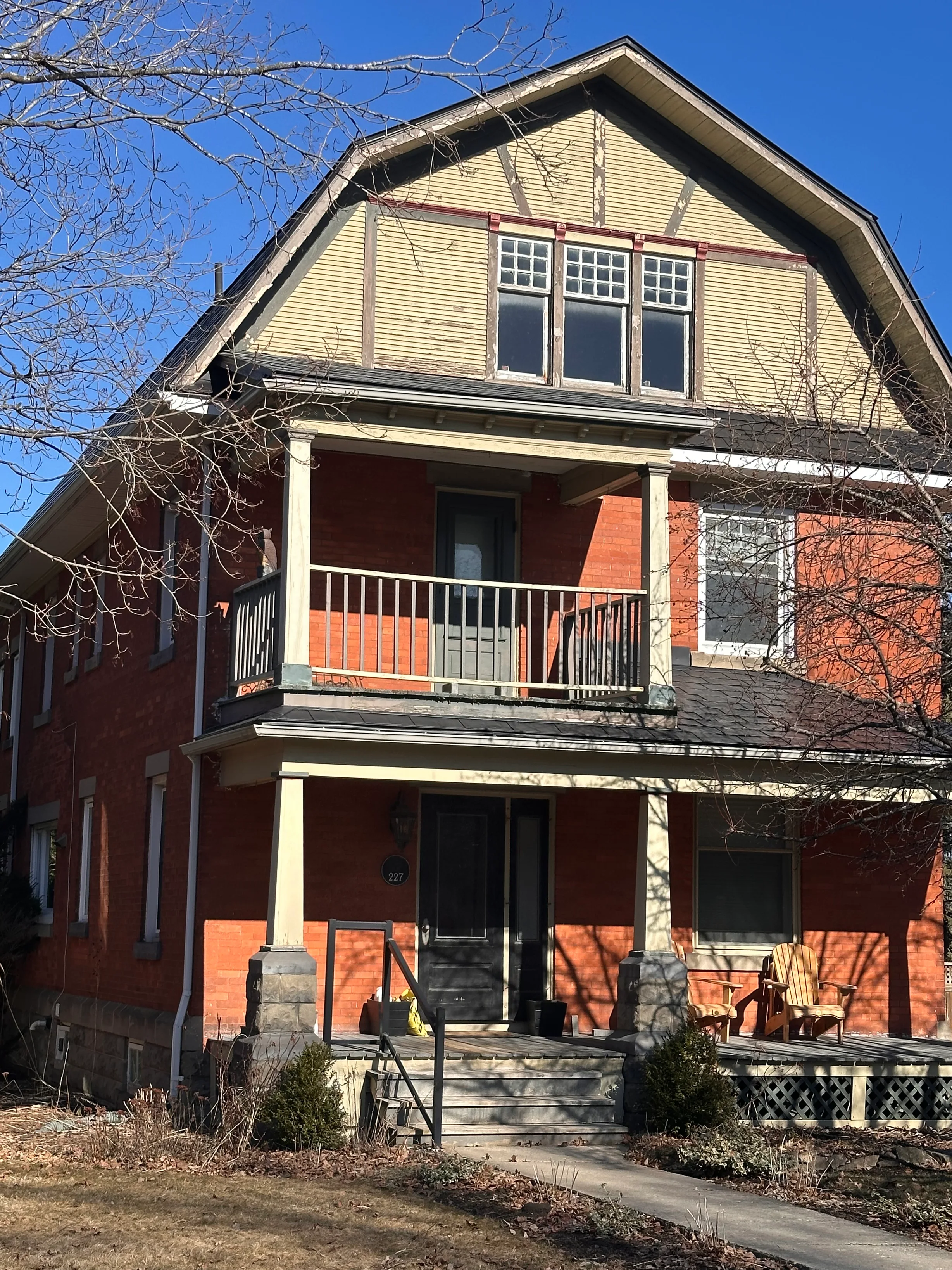 Black Interlock Slate aluminum roof on a red two-storey Craftsman home with dormers among tall, Kemptville, Ontario